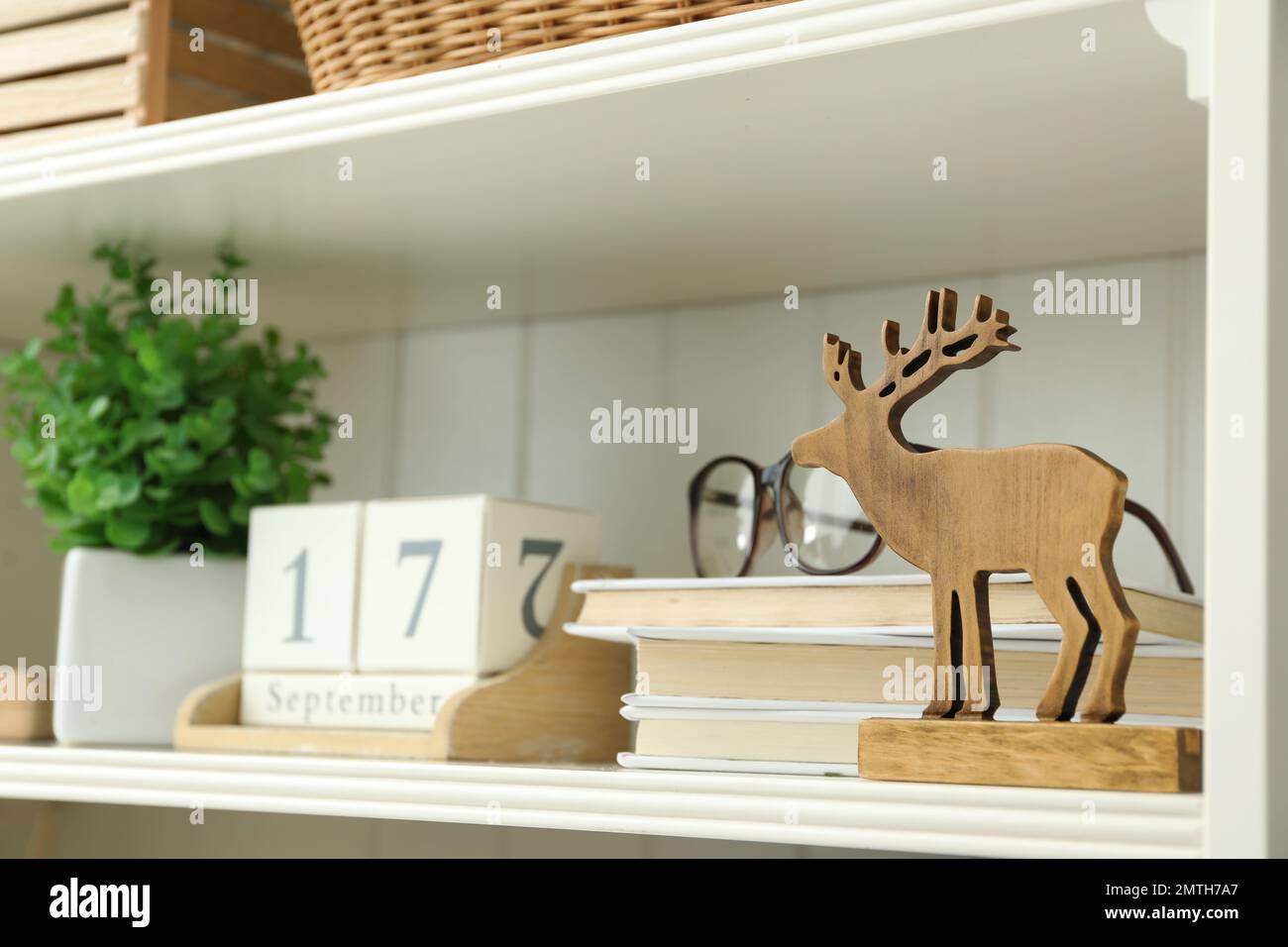 Estantería blanca con figura de ciervo de madera, libros y calendario Foto de stock