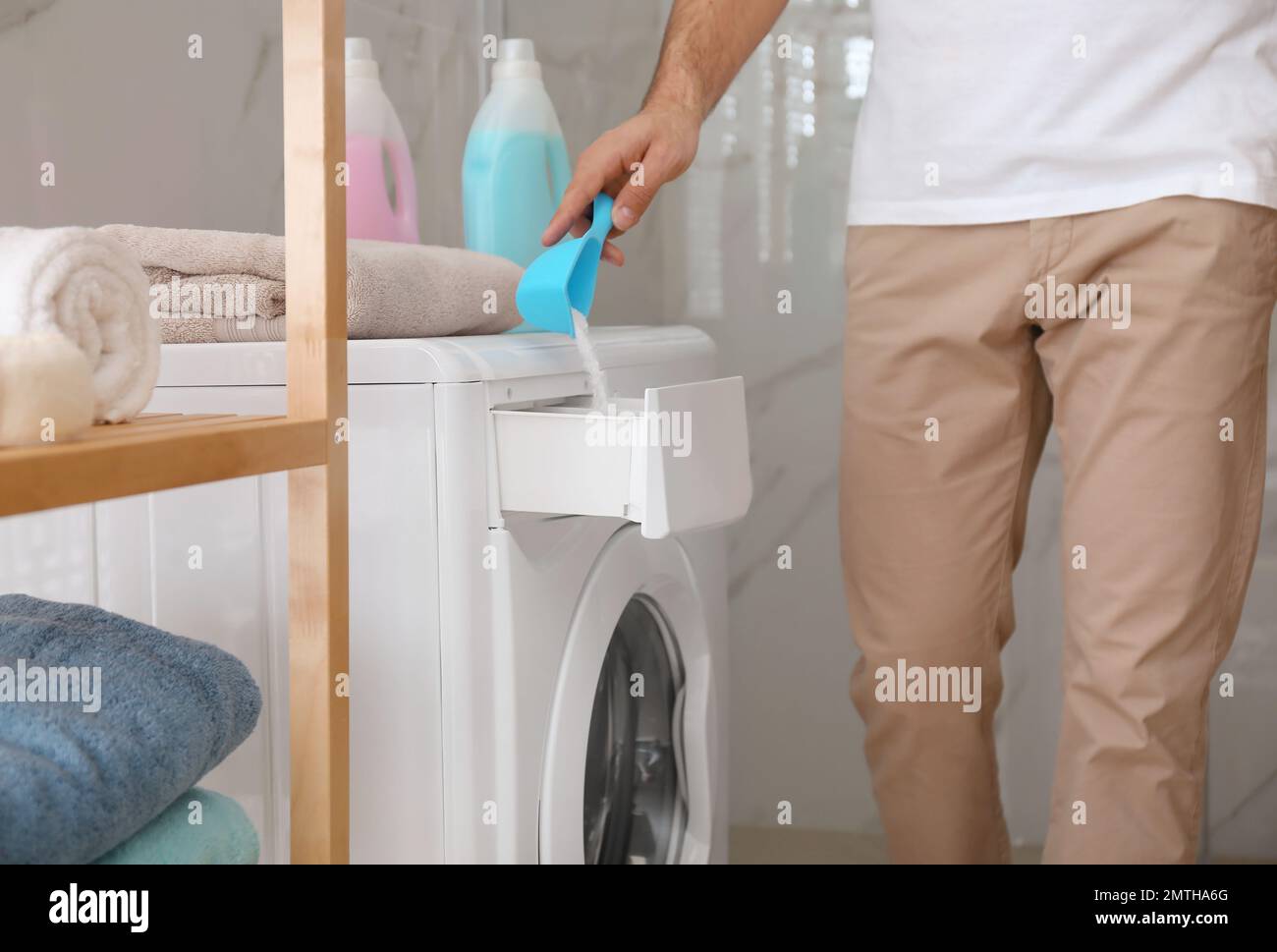 Hombre vertiendo detergente de ropa en el cajón de la lavadora en el baño,  primer plano Fotografía de stock - Alamy