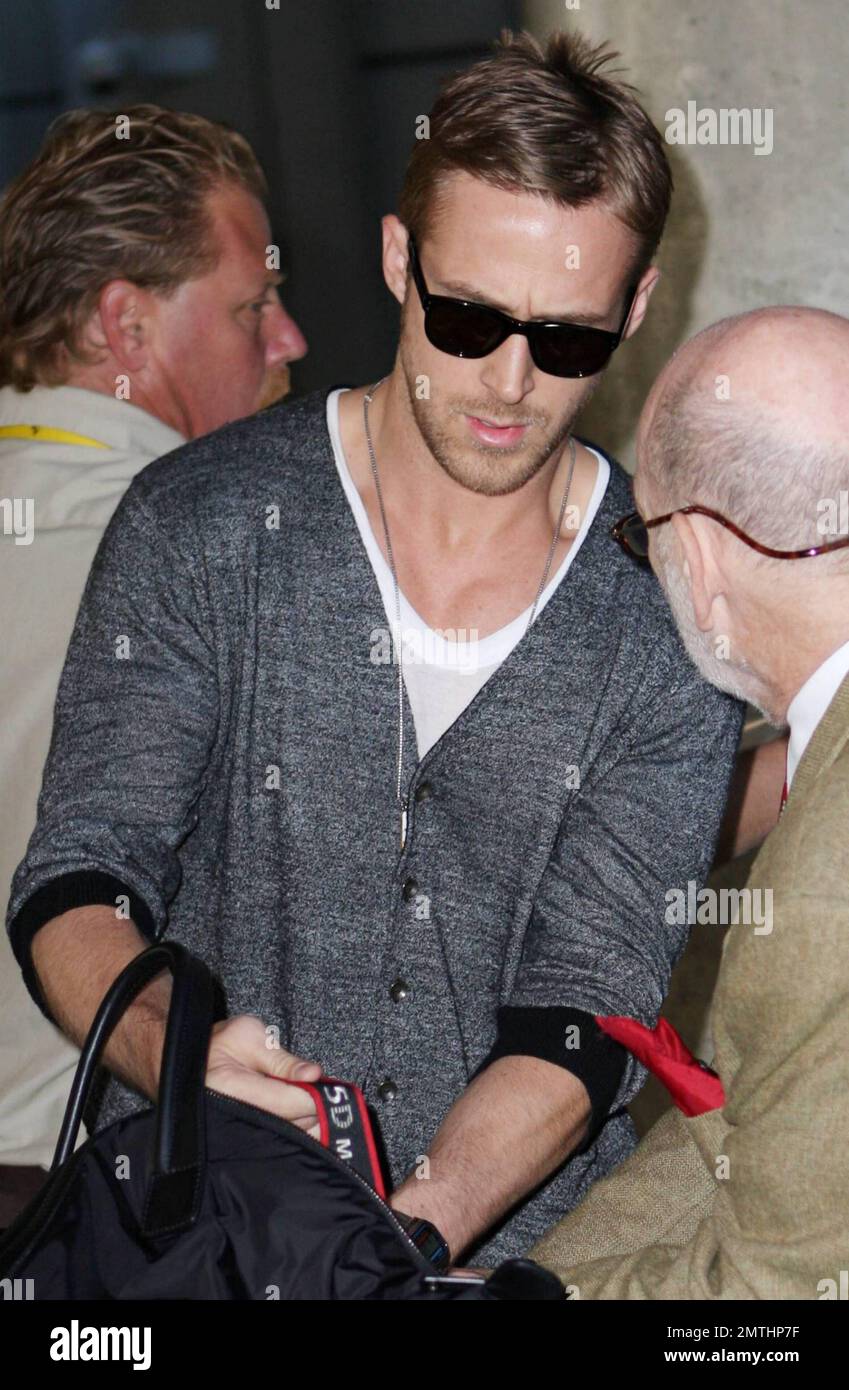 El actor Ryan Gosling se ve muy elegante con un par de zapatos blancos y un  cárdigan gris cuando llega a LAX después de un vuelo desde Cannes, Francia.  Gosling estuvo en