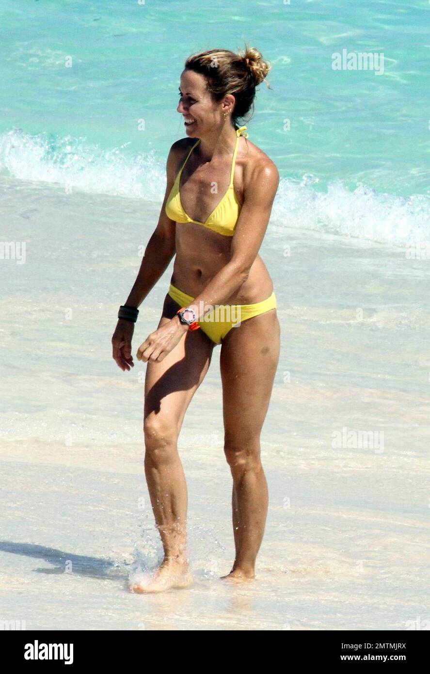 La rockera Sheryl Crow luce un bikini amarillo mientras retoza en el surf  con su hijo Wyatt mientras está de vacaciones en el Caribe. 5/28/10  Fotografía de stock - Alamy