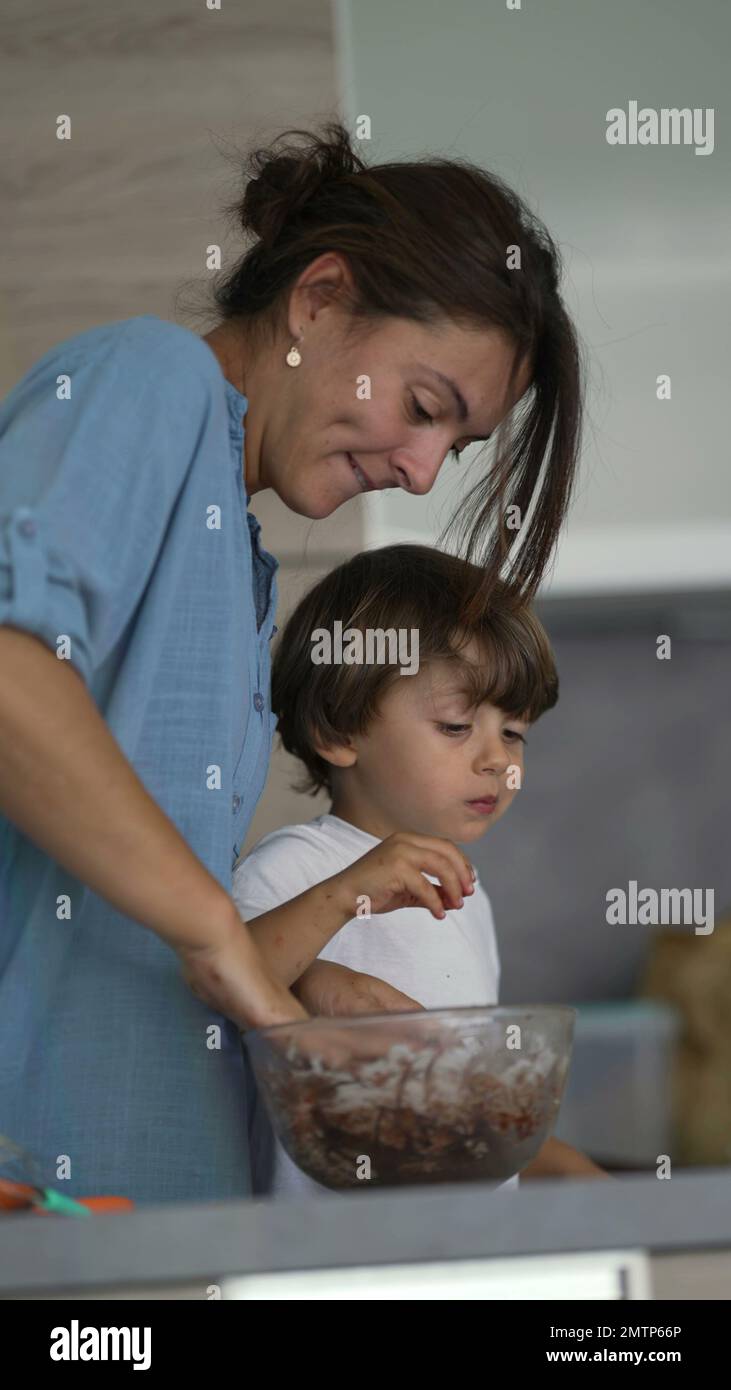 Madre mezclando ingredientes a mano con el niño comiendo masa. Padre y niño  joven preparando y horneando alimentos juntos en vídeo vertical Fotografía  de stock - Alamy