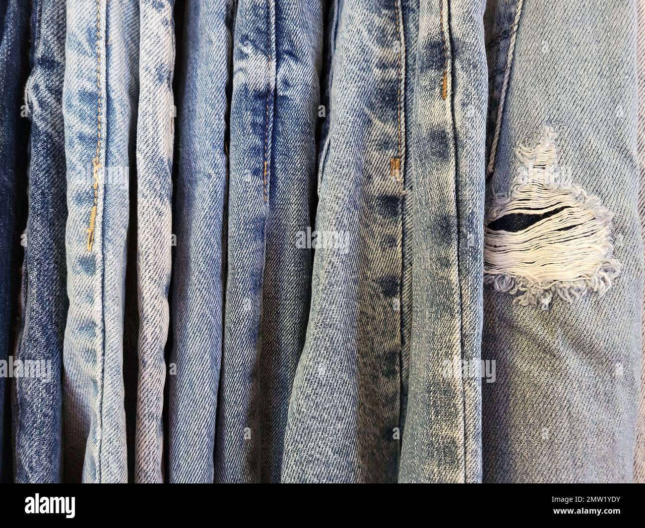 Primer plano de jeans azules desgastados con un agujero deshilachado Foto de stock