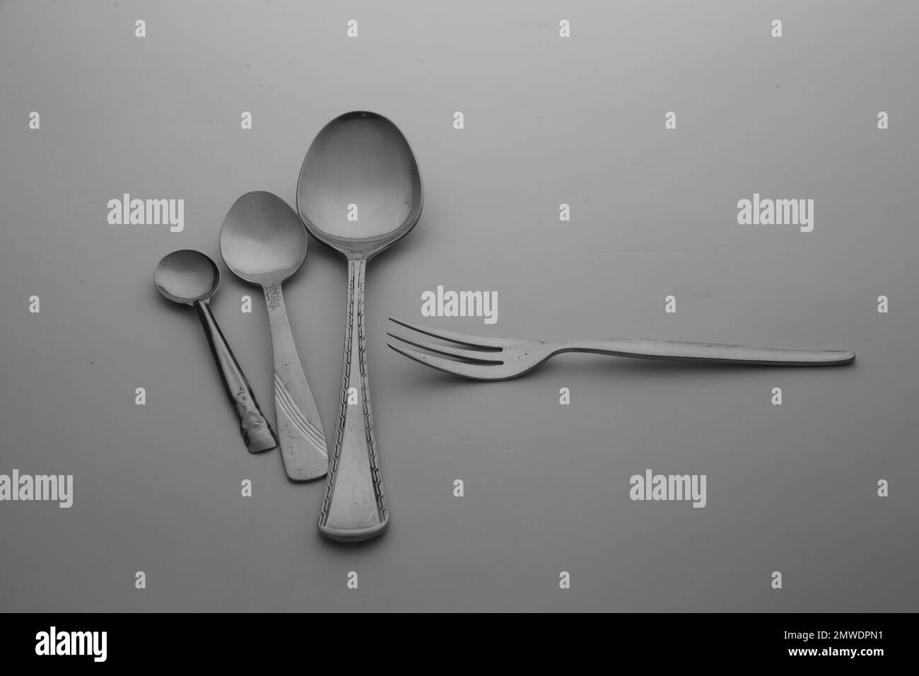 La cuchara de plata, tenedores y cubiertos de cuchillo aislados en el fondo de mesa gris vacío Foto de stock