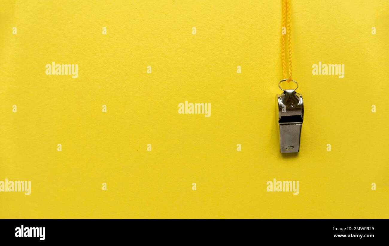Silbato colgado en una pared amarilla. Foto de stock