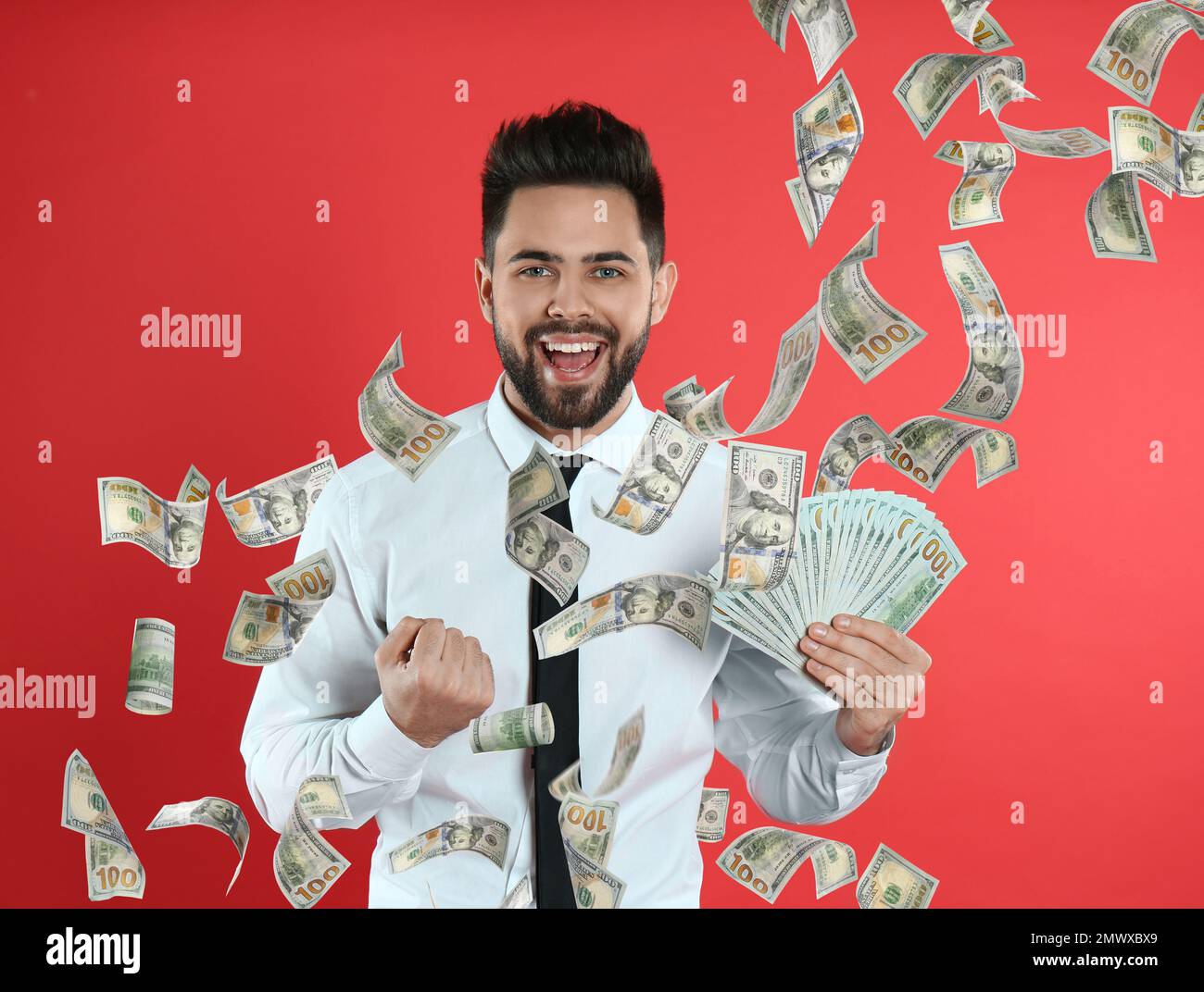 Hombre joven feliz con dinero sobre fondo rojo Foto de stock