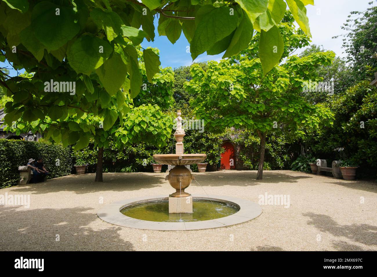 Una fuente en el medio de un patio de grava rodeado de árboles de frijol indio o Catalpa bignonioide en el patio de grava en el conde de coleccionista Foto de stock