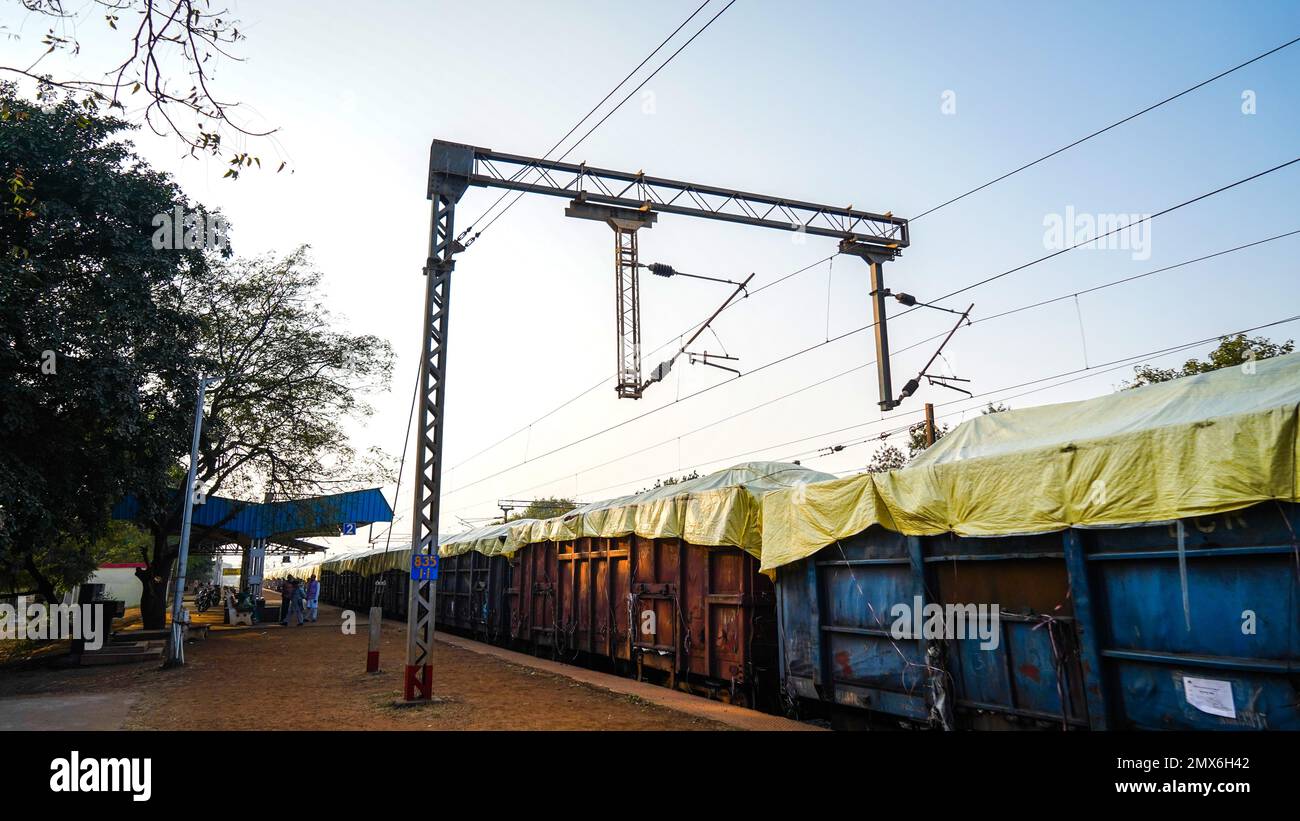 tren de carga de estación de ferrocarril indio de pie en la unión, poste de metal con cable eléctrico, tiro de ángulo bajo, tecnología de transporte de locomotora Foto de stock