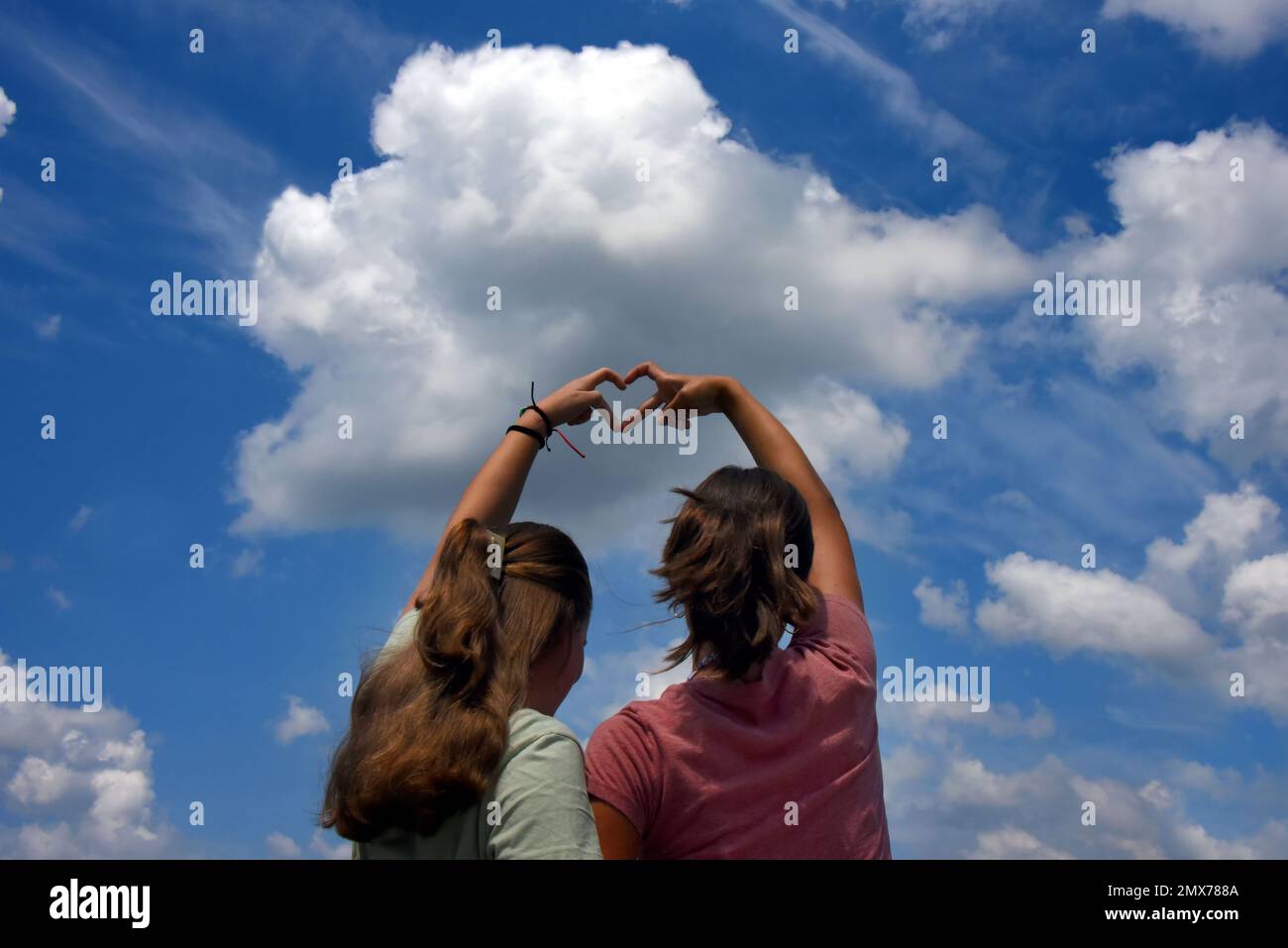 Dos hermanas, adolescentes, unen sus manos para formar un corazón. Ellos están expresando su amor por la naturaleza y el cielo, por los cielos, o por cada otro Foto de stock