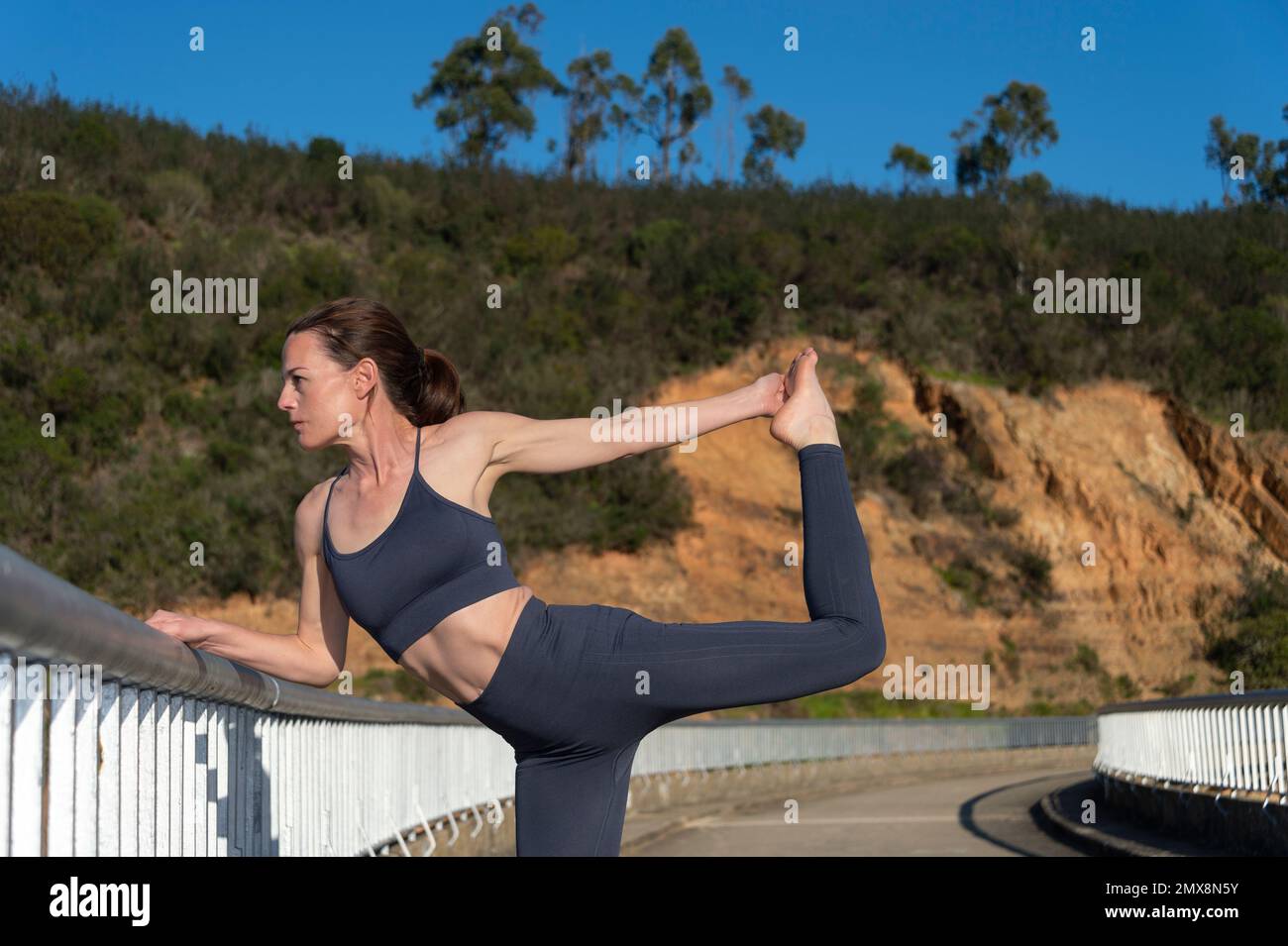Mujer practicando yoga y estirando afuera, pose bailarina. Foto de stock