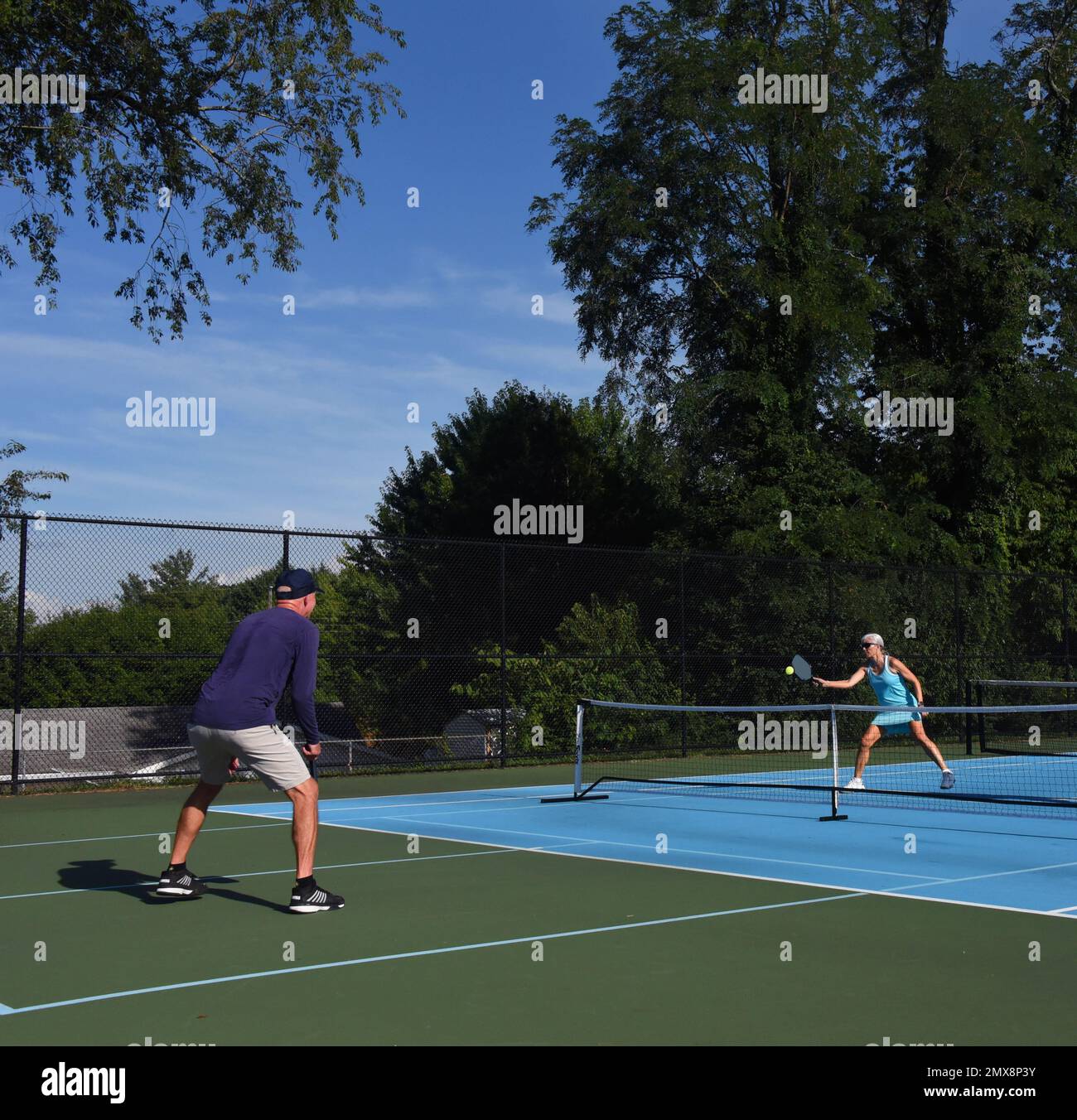 Dos jugadores, hombre y mujer, volean la bola de pepinillos de ida y vuelta durante un partido en Asheville, Carolina del Norte. Foto de stock