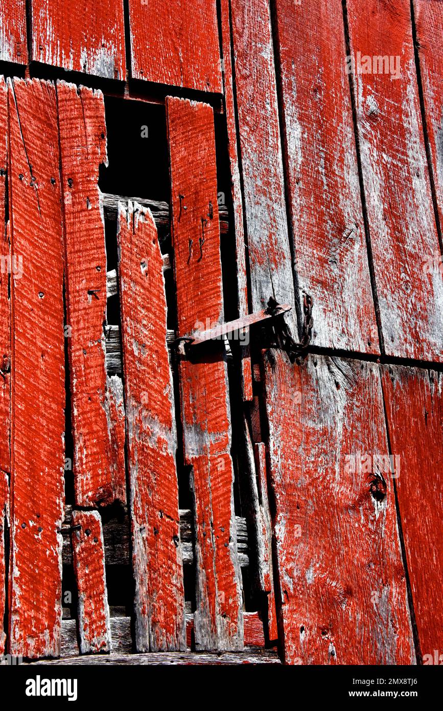 Oxidado y viejo, el hardware de metal mantiene la puerta del loft cerrada. El granero es rojo, de madera y erosionado con la edad. Foto de stock