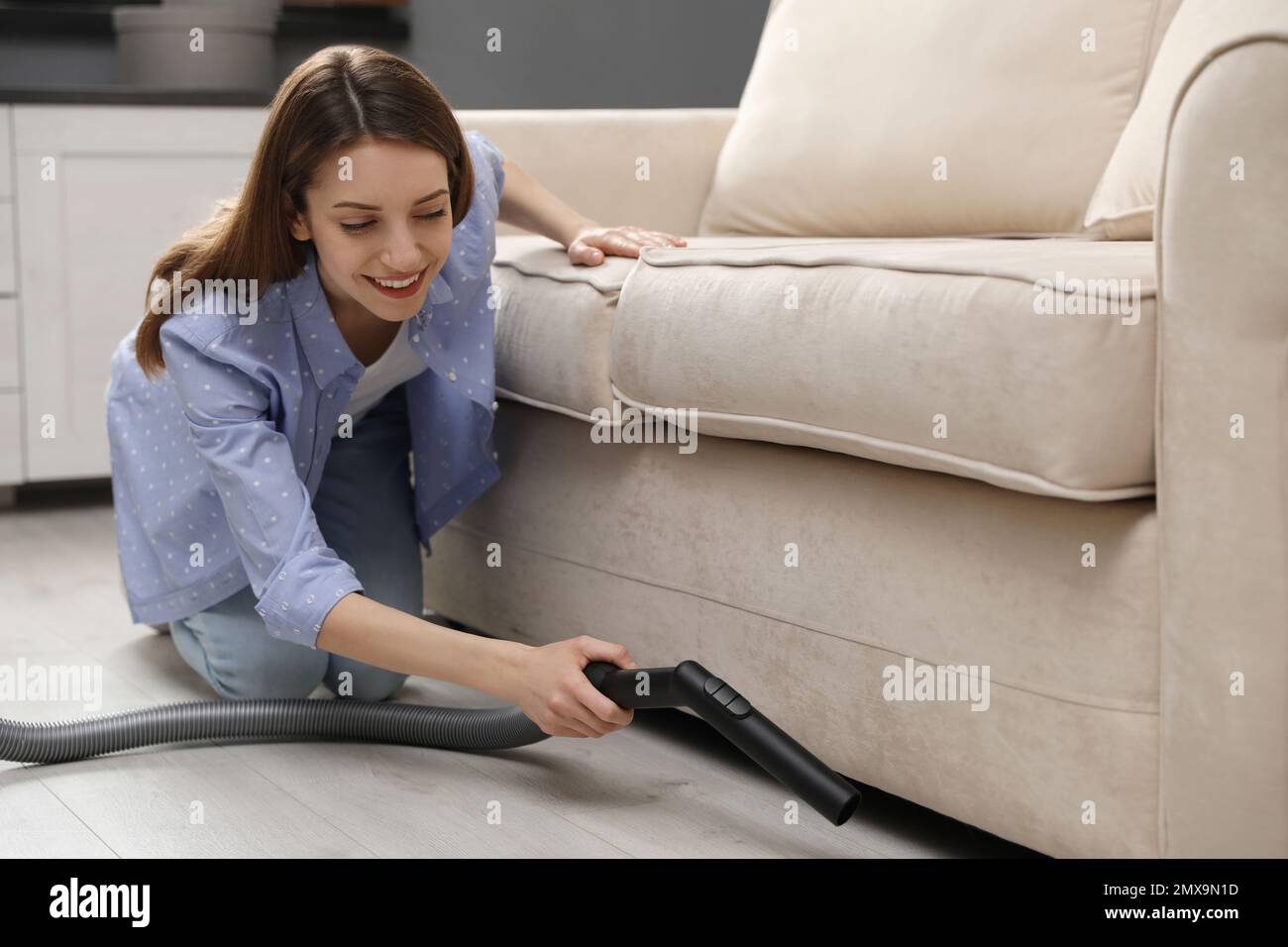 Mujer joven con aspiradora recargable sentada en el sofá y en casa. La  chica trata de doblar la aspiradora según las instrucciones Fotografía de  stock - Alamy