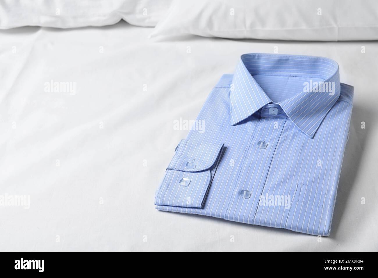 Elegante camisa azul claro en la cama, espacio para el texto. Servicio de  tintorería Fotografía de stock - Alamy