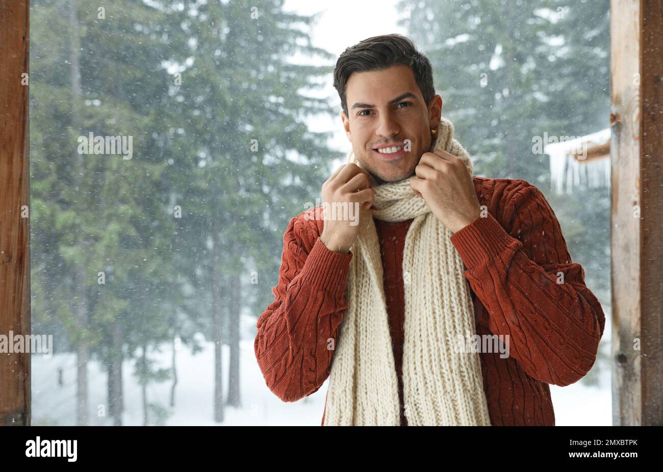 Hombre guapo con suéter caliente y bufanda al aire libre en día nevado.  Temporada de invierno Fotografía de stock - Alamy