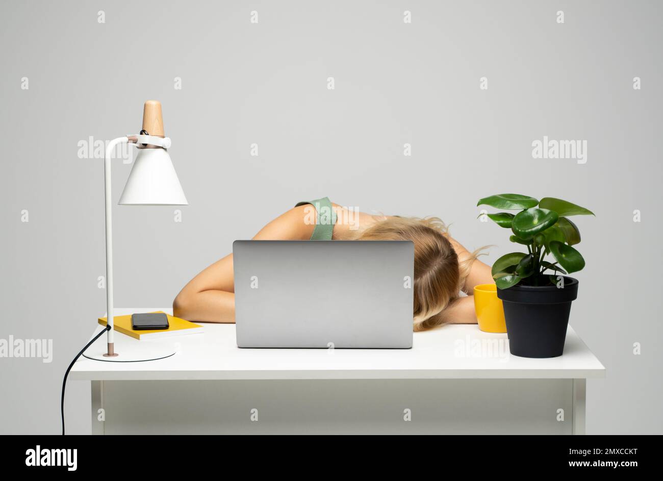 La joven mujer agotada frustrada puso su cabeza sobre la mesa sentó el  trabajo en el escritorio blanco con el ordenador portátil contemporáneo de  la pc. Logro de la carrera empresarial Fotografía