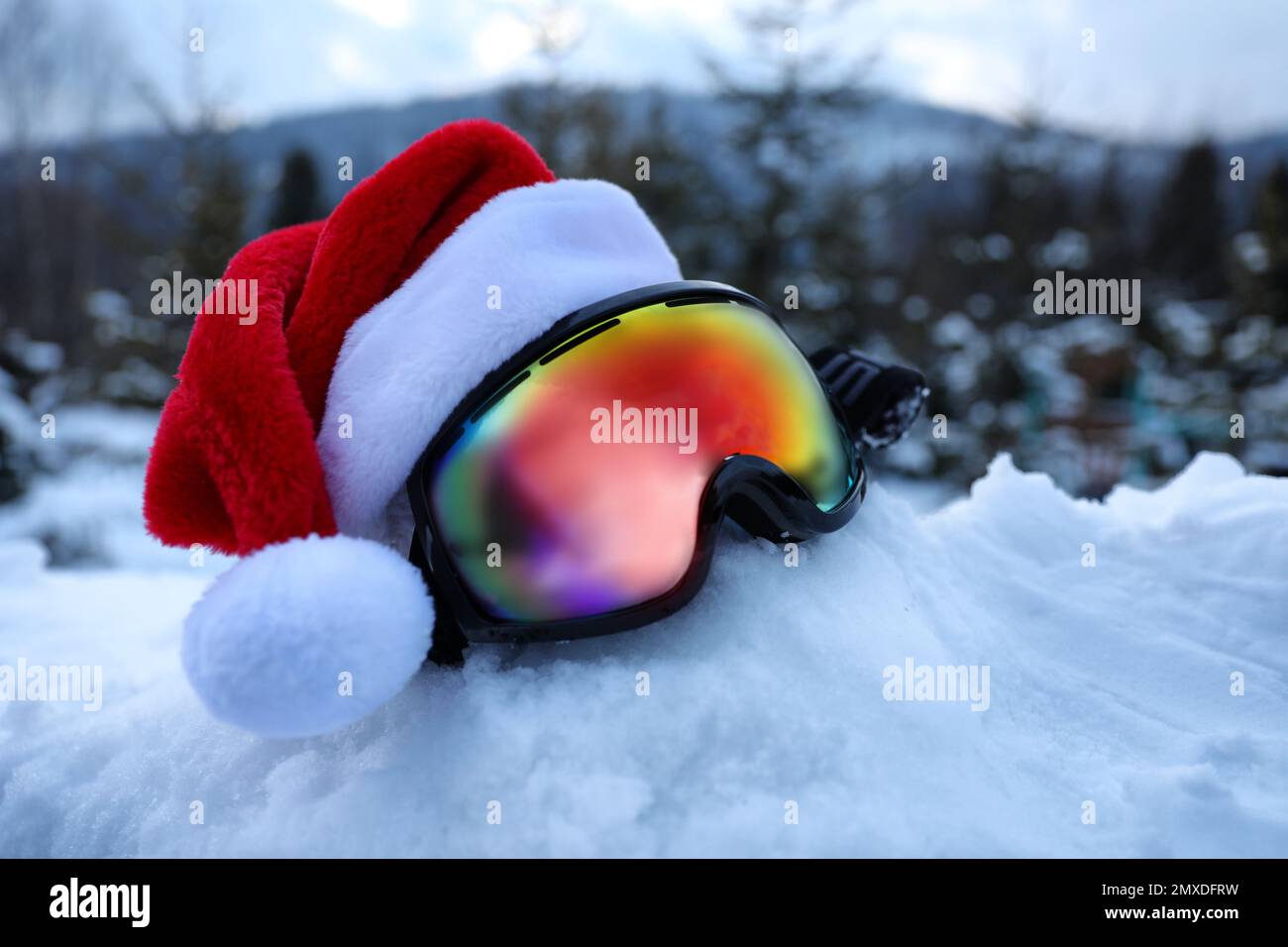Elegantes gafas de esquí con sombrero de Papá Noel en la nieve al aire libre. Equipamiento deportivo de invierno Foto de stock