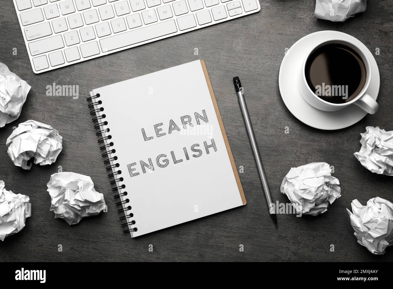 Cuaderno con texto Aprende inglés, teclado y bolas de papel arrugadas