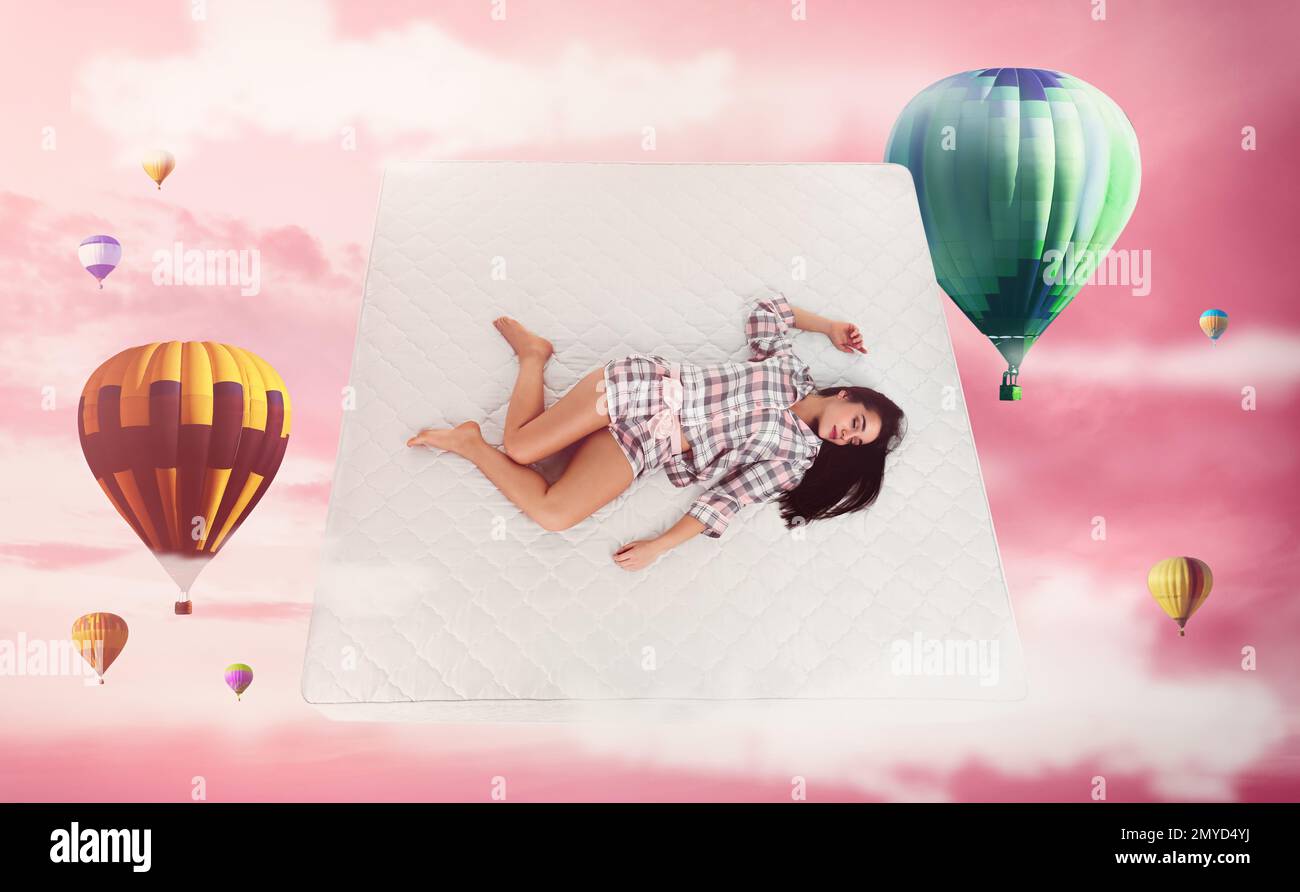 Dulces sueños. Cielo nublado rosa con globos de aire caliente alrededor de la mujer joven durmiente Foto de stock
