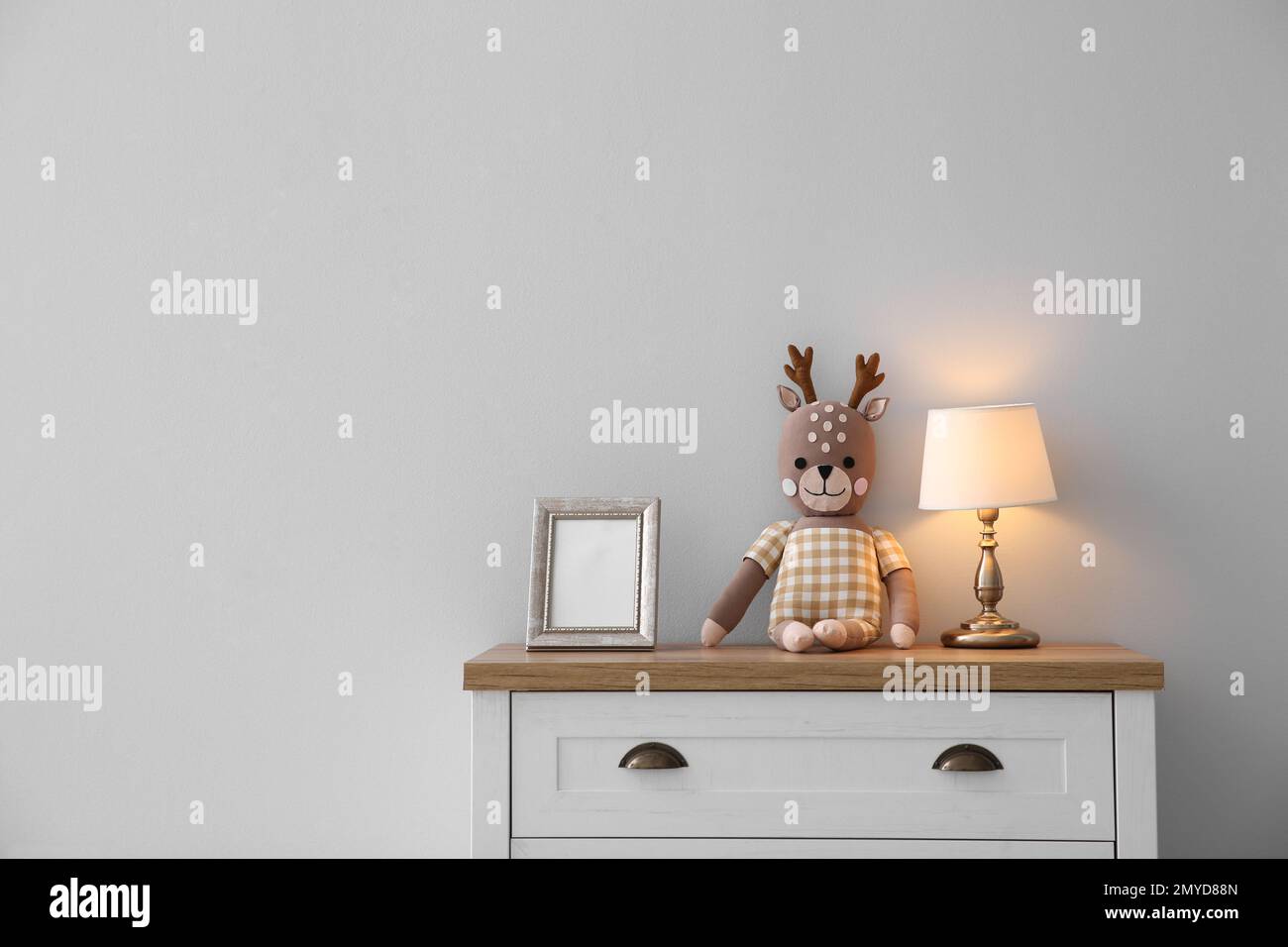 Moderno cofre blanco de cajones cerca de la pared de luz en la habitación infantil, espacio para el texto. Diseño de interiores Foto de stock