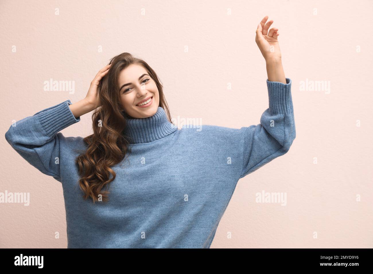 Hermosa mujer joven con suéter azul cálido sobre fondo rosa claro  Fotografía de stock - Alamy