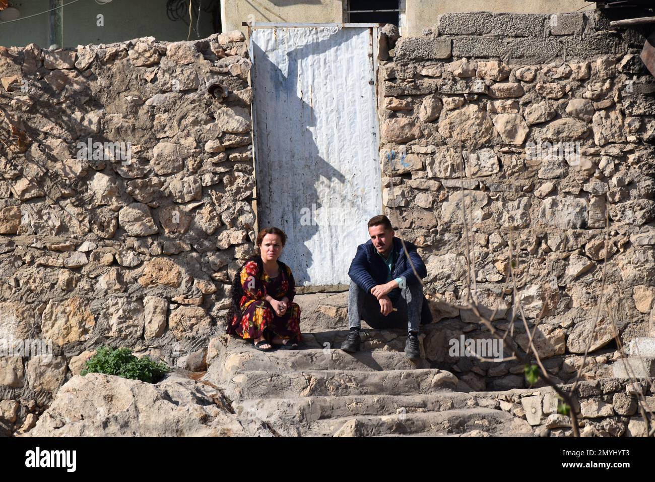 Una pareja sentada en los escalones fuera de su casa en el Kurdistán iraquí Foto de stock