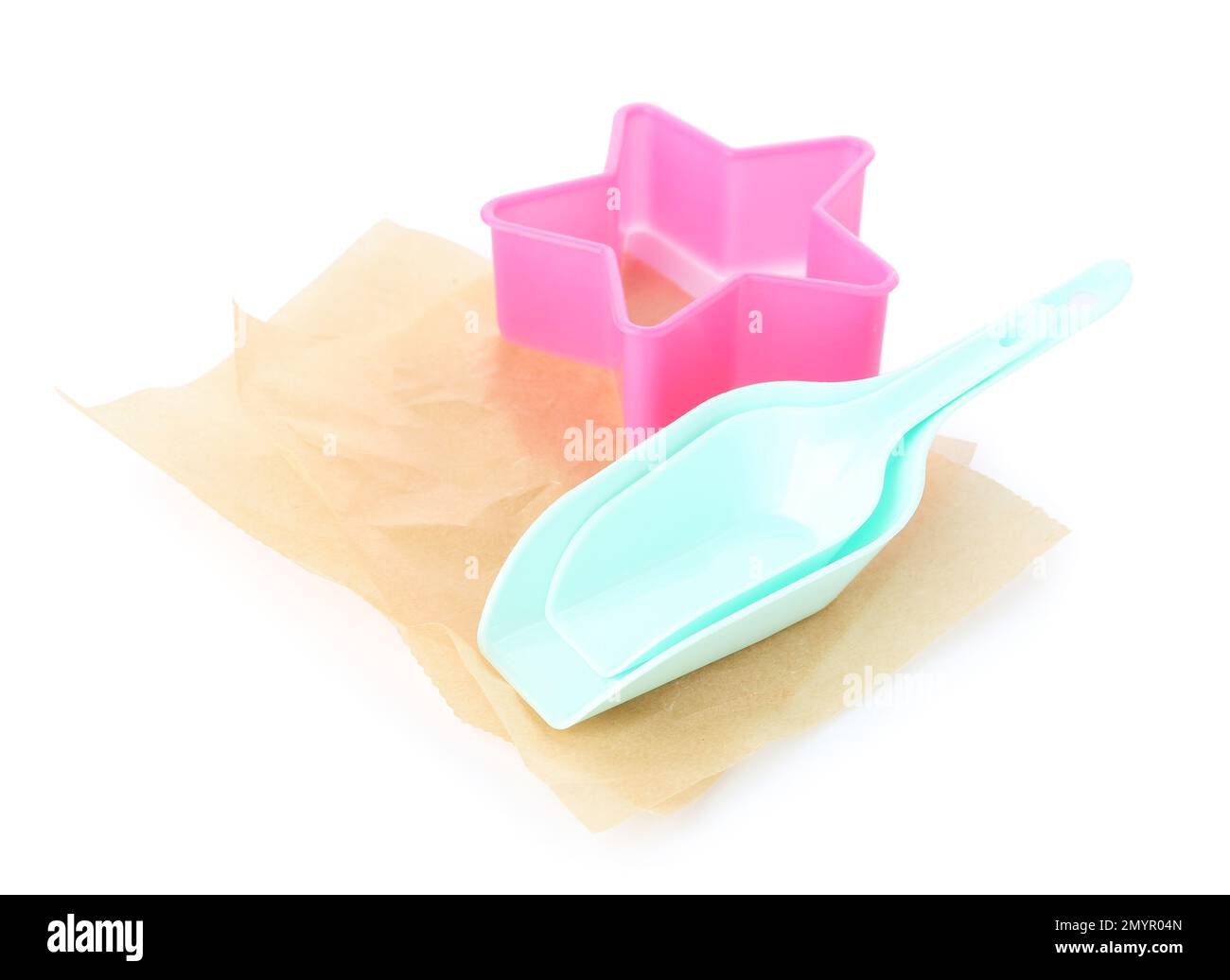 Hojas de papel de hornear, cucharadas y cortador de galletas sobre fondo blanco Foto de stock