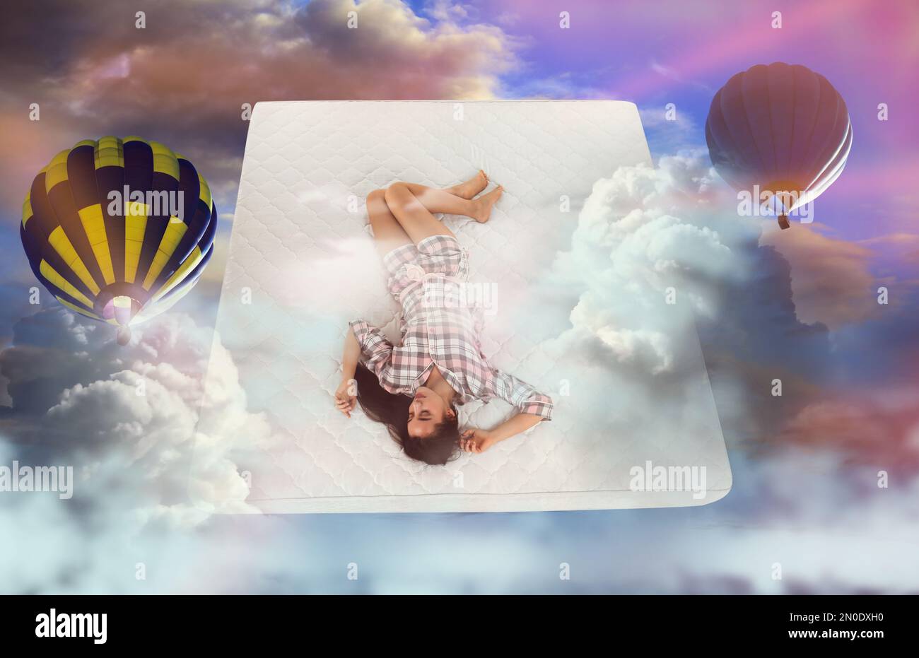 Dulces sueños. Cielo nublado brillante con globos de aire caliente alrededor de la mujer joven durmiente Foto de stock