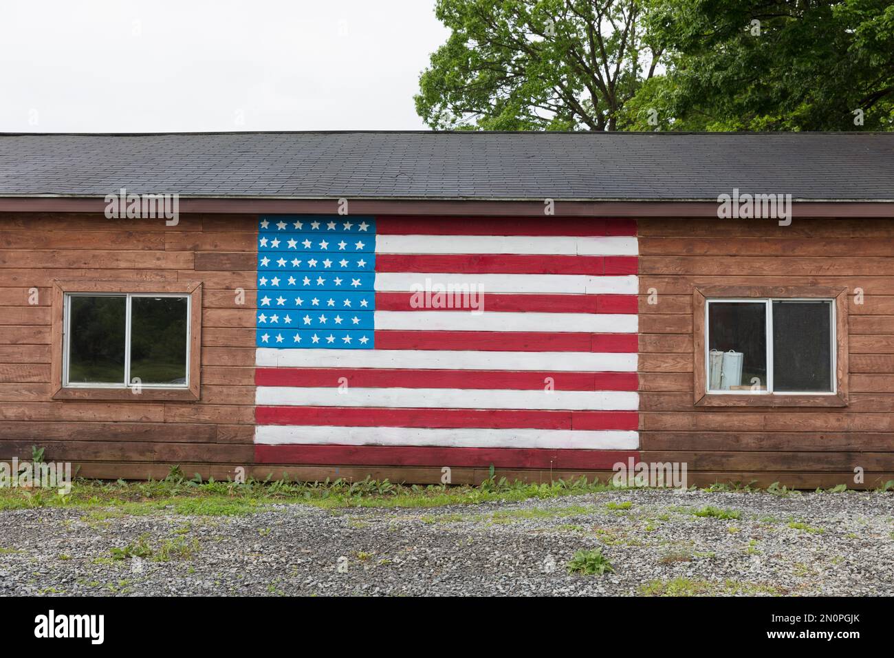 Una bandera americana pintada en un edificio vacío en una calle de un pueblo pequeño. Foto de stock
