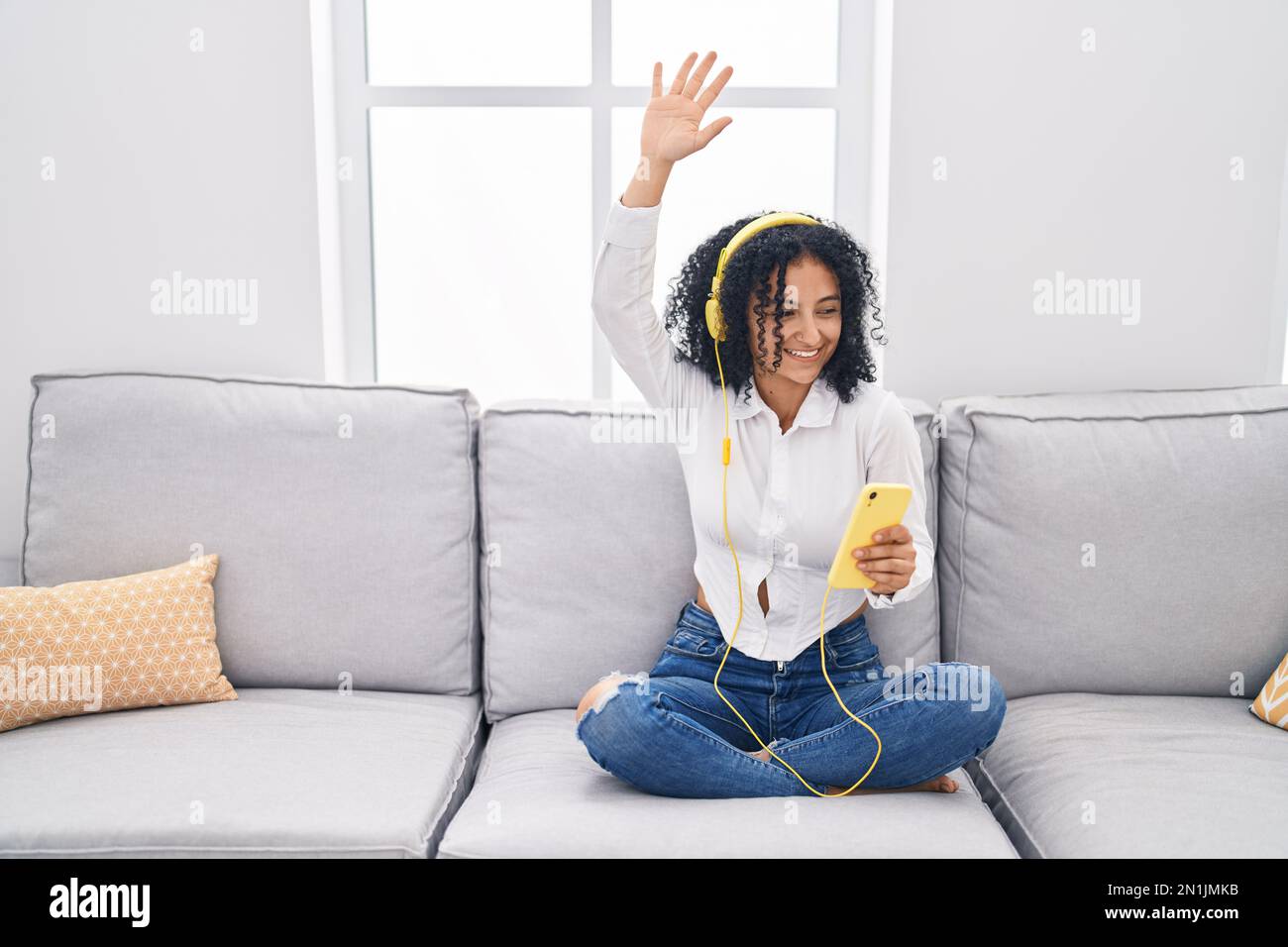 Una joven hispana escuchando música sentada en el sofá de la casa  Fotografía de stock - Alamy