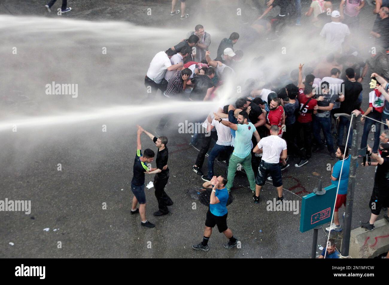 Lebanese activists shout antigovernment slogans as they are sprayed by