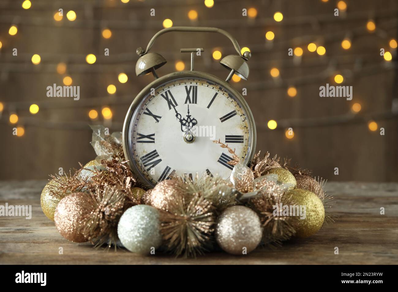 Reloj despertador vintage con decoración en mesa de madera contra luces  borrosas de Navidad. Cuenta atrás de Año Nuevo Fotografía de stock - Alamy