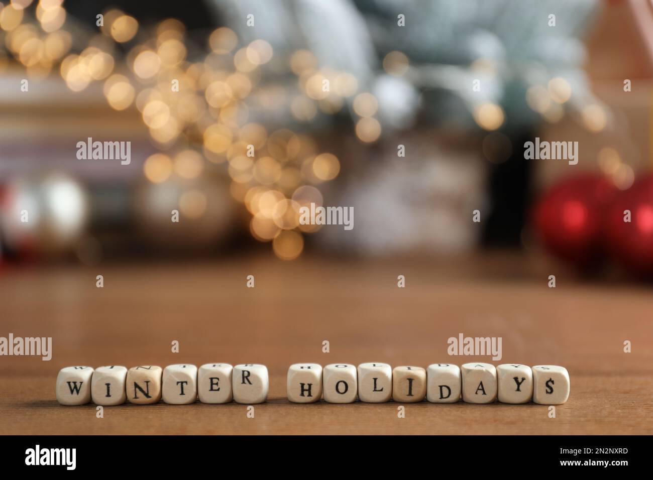 Cubos con frase Vacaciones de invierno y decoración borrosa de Navidad en el fondo. Espacio para texto Foto de stock