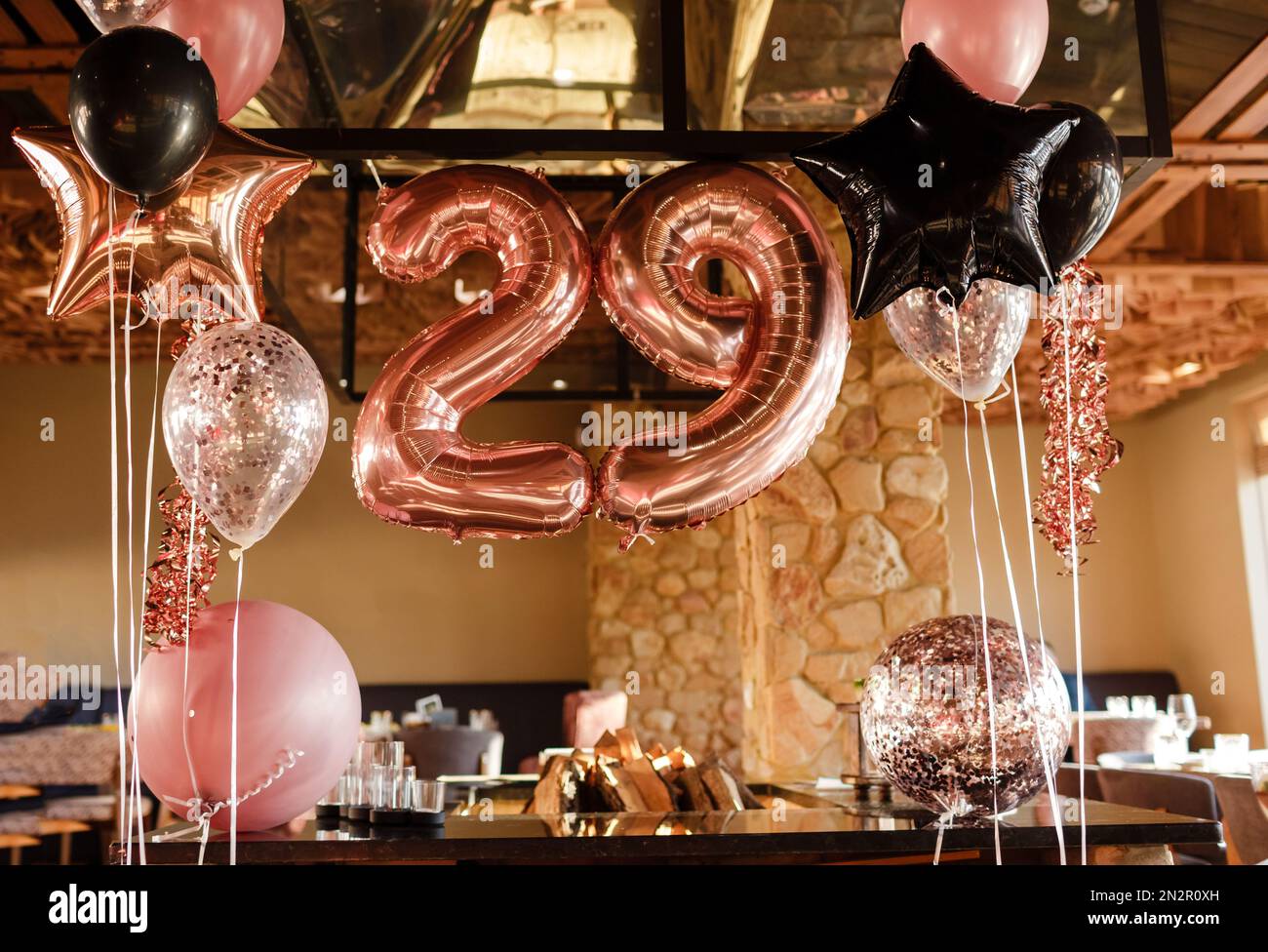 Sala de restaurante decorada para una fiesta de cumpleaños con globos rosa,  negro y transparente de diferentes tamaños, gran inflable número 29.  Captura de fotos Fotografía de stock - Alamy