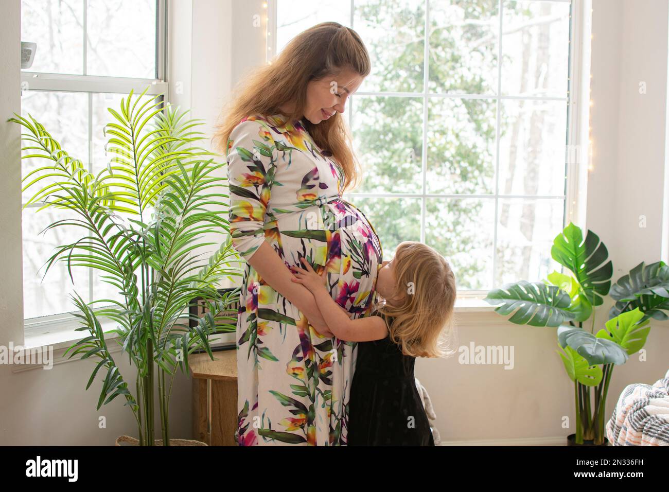 Niña besando el vientre embarazada de su madre. Familia, concepto de embarazo. Foto de stock