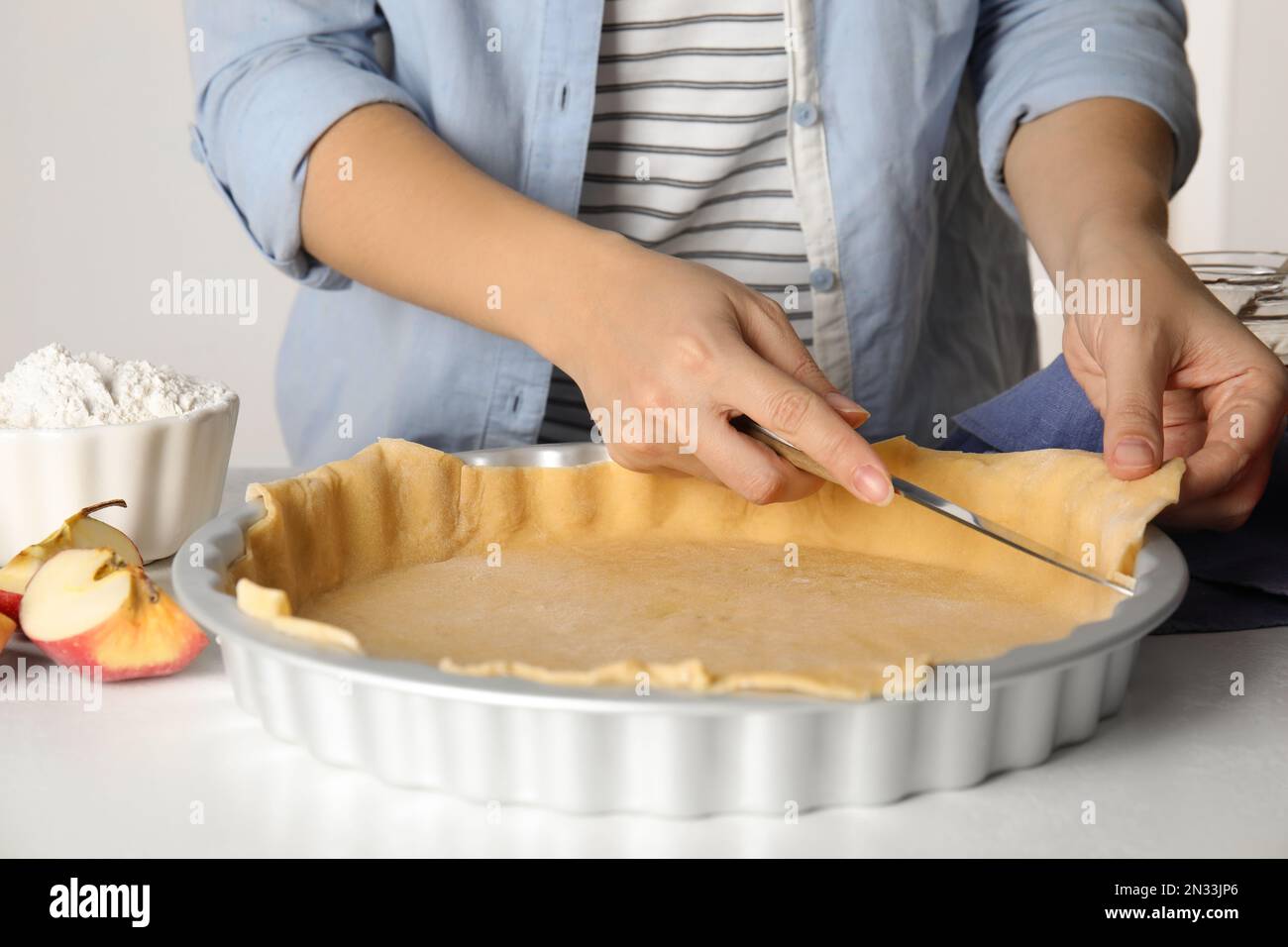 Mujer cortando sobras de masa para el tradicional pastel de manzana