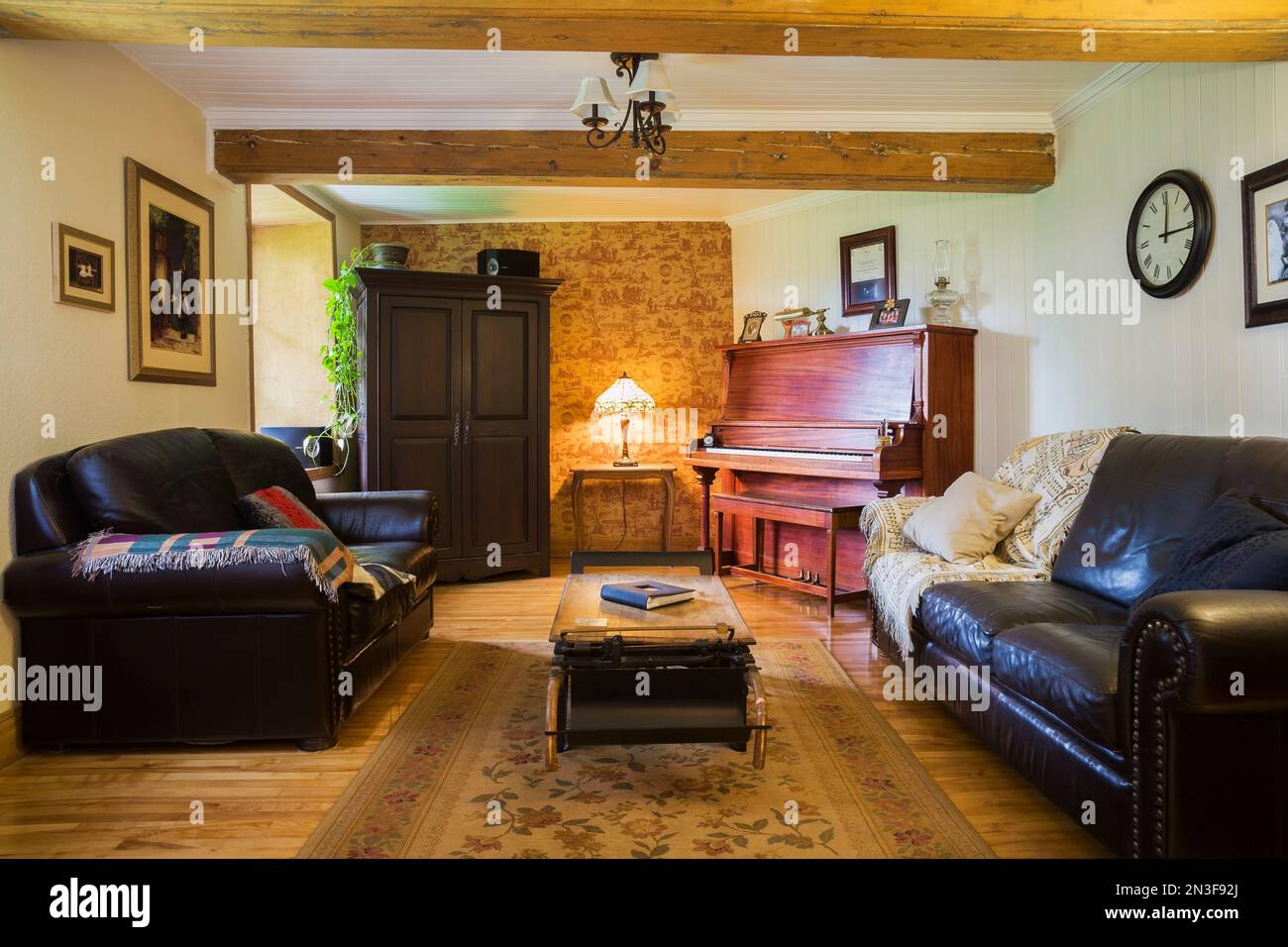Sala de música con sofás de cuero marrón oscuro, piano vertical