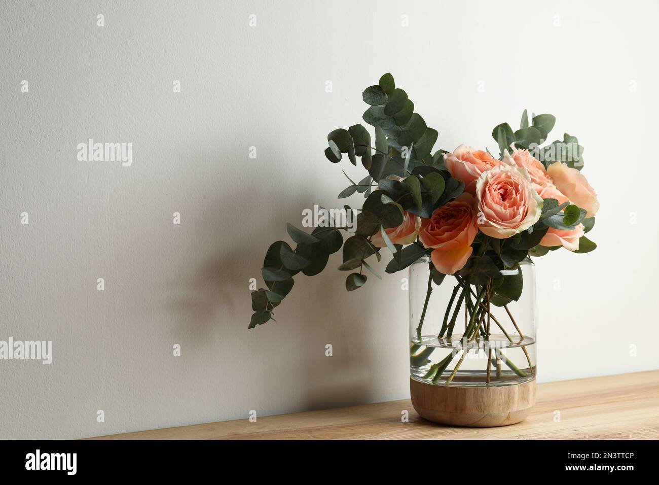 Ramo con hermosas flores en jarrón de vidrio sobre mesa de madera sobre  fondo blanco. Espacio para texto Fotografía de stock - Alamy