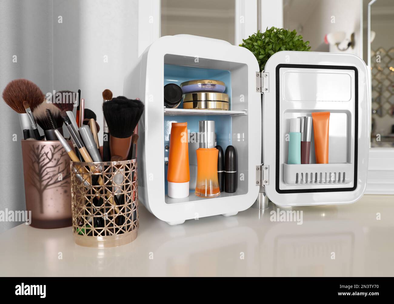 Mini nevera con productos cosméticos en la mesa de tocador blanca  Fotografía de stock - Alamy