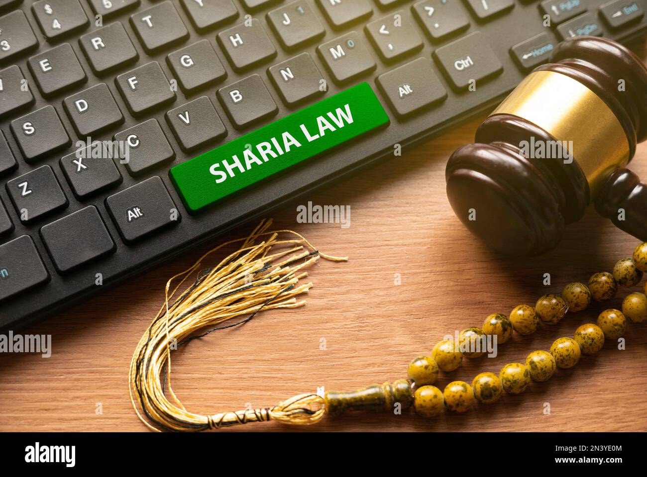 Mazo, cuentas de rosario y teclado de computadora escrito con Sharia Law. Foto de stock