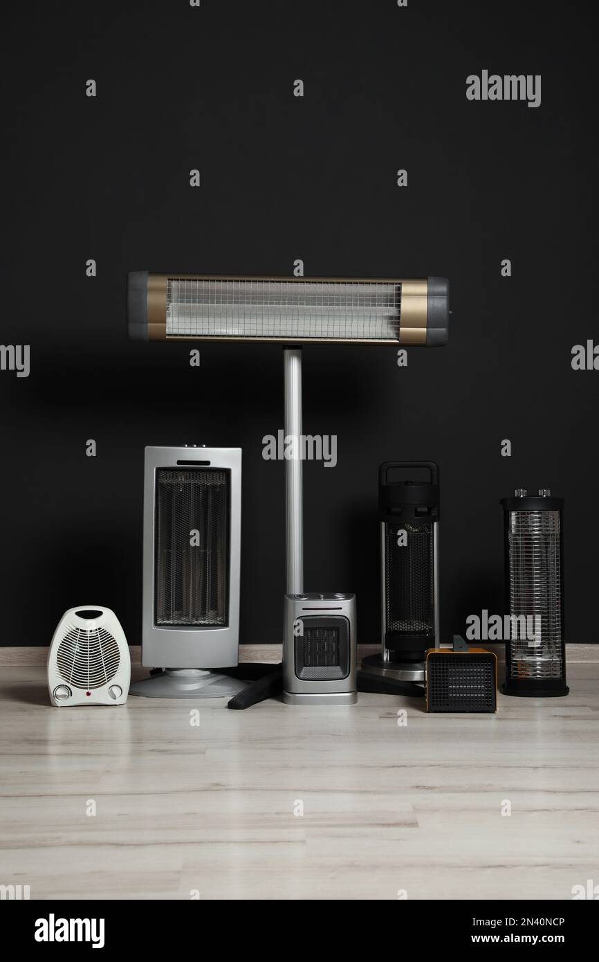 Conjunto de diferentes calentadores eléctricos modernos cerca de la pared  negra Fotografía de stock - Alamy