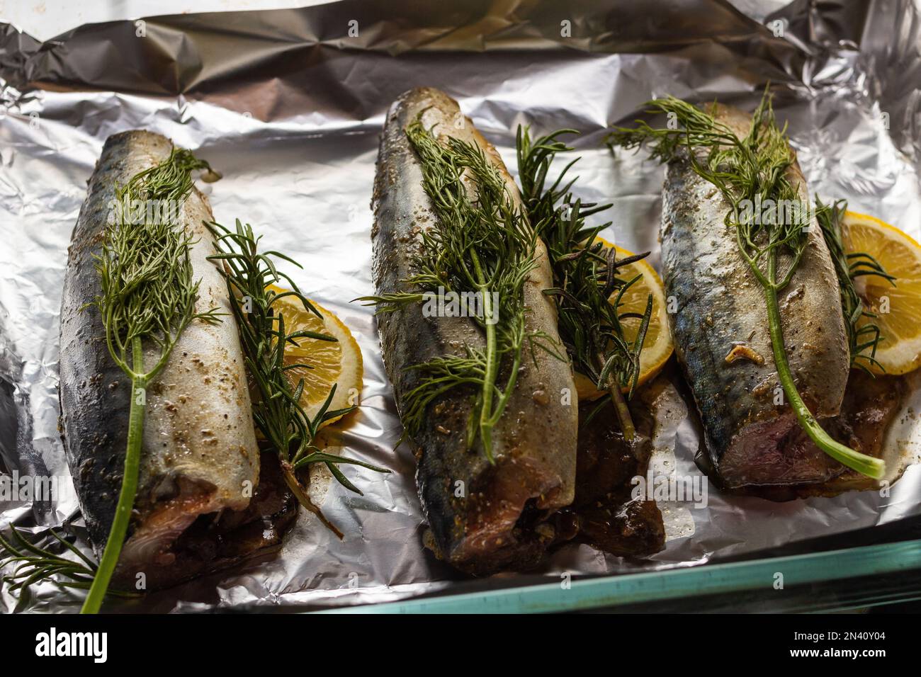 pescado caballa con romero y plato de limón, varios objetos, servido  acostado en la hoja para hornear en el horno en la  de receta  de pescado con romero y limón Fotografía