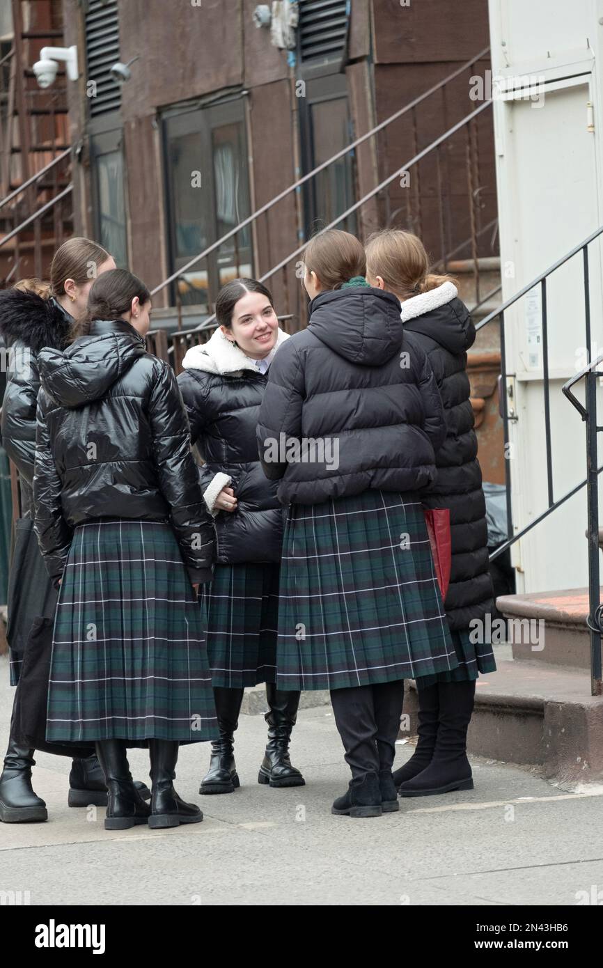 Las niñas judías jasídicas que llevan el uniforme de su escuela se detienen para charlar en su camino a casa. Llevan modestas faldas largas a cuadros. En Brooklyn, New Yor. Foto de stock