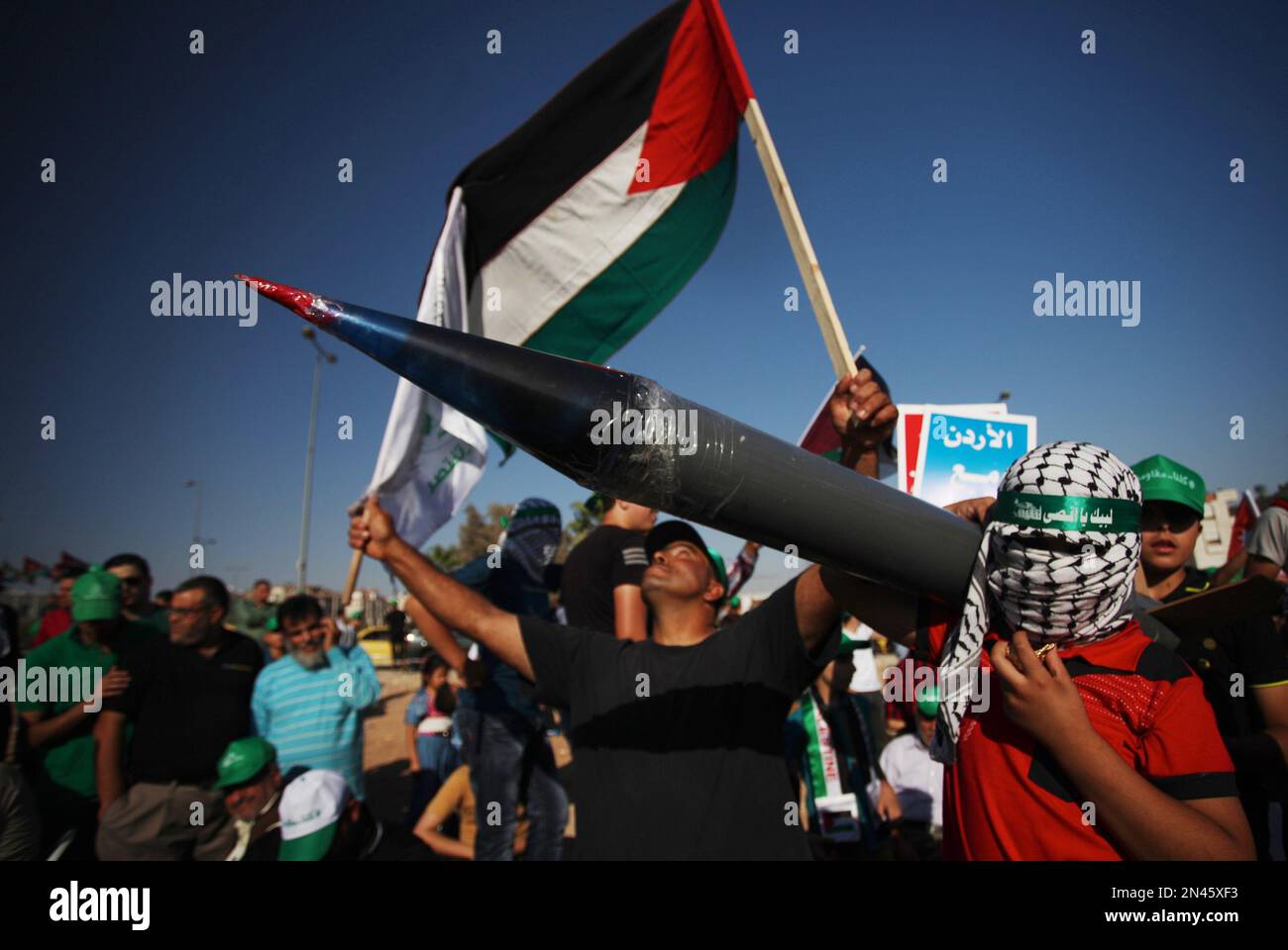A masked youth carries a rocket decoy, during a celebration by the