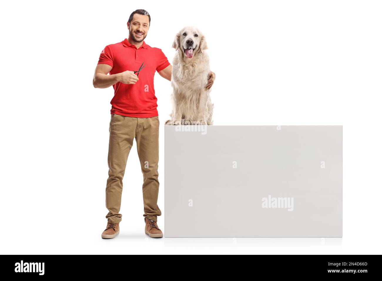 Hombre sosteniendo tijeras y abrazando a un perro retriever aislado sobre fondo blanco Foto de stock