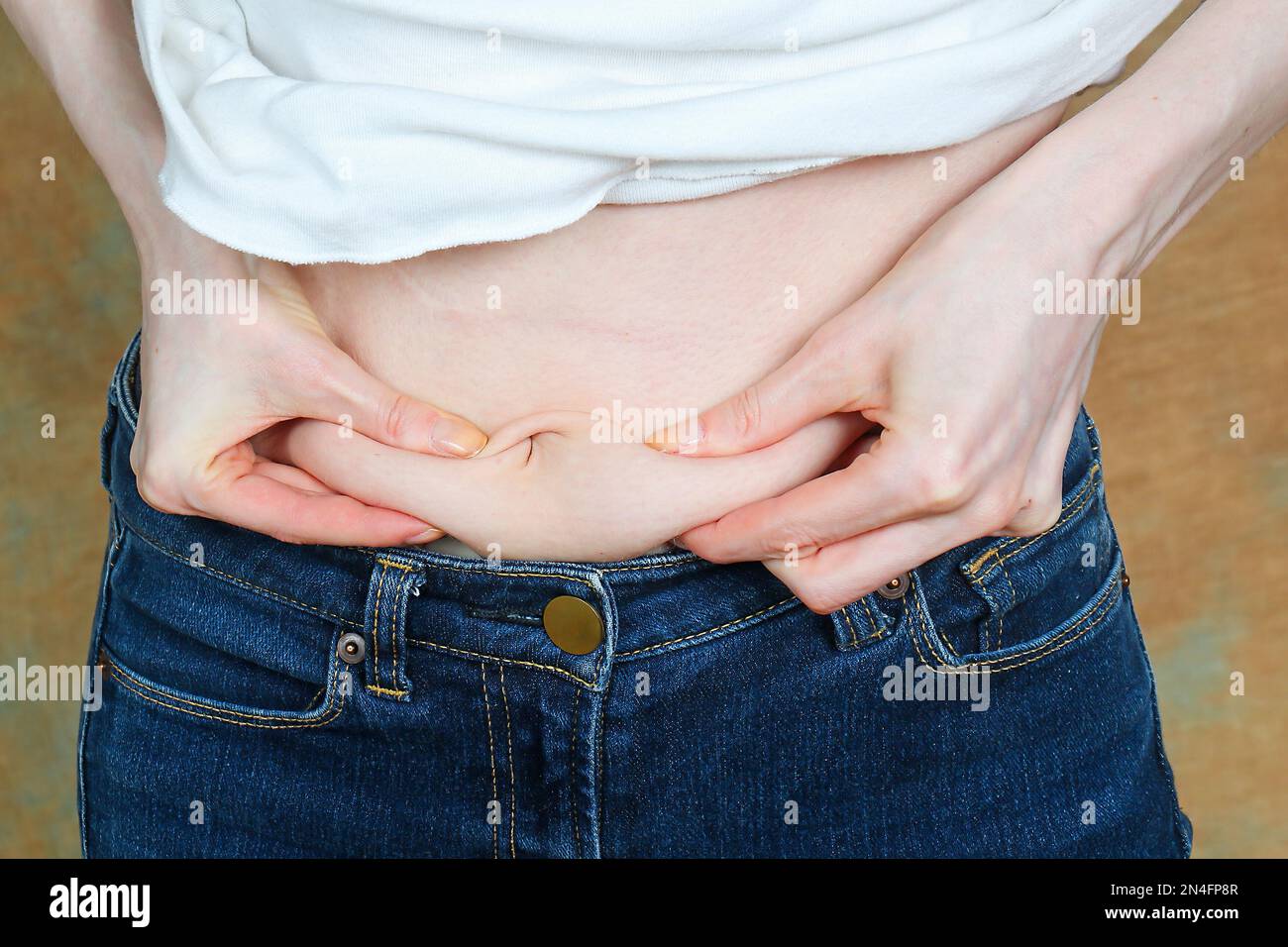 Mujer hinchada sosteniendo grasa del vientre en su estómago Foto de stock