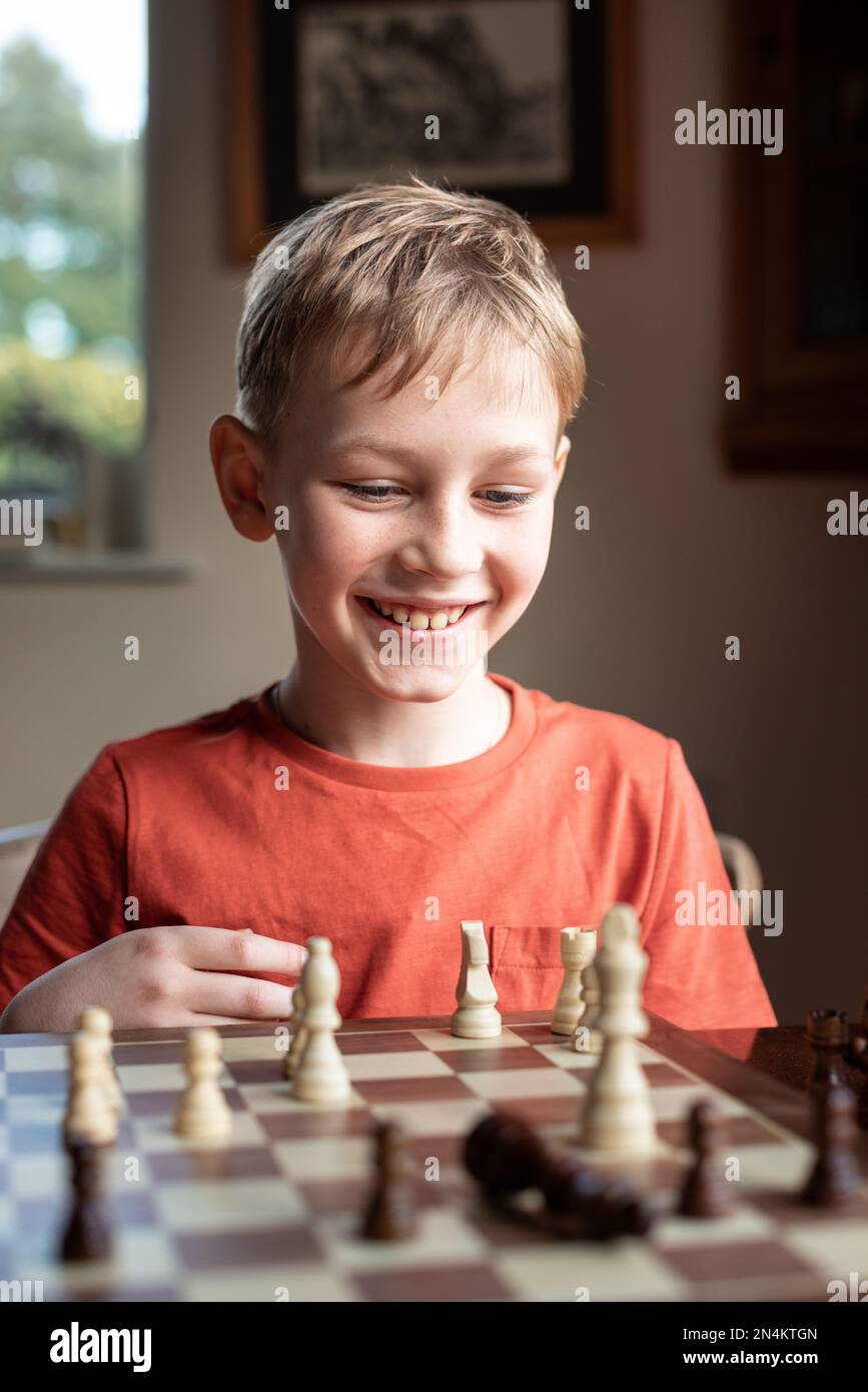 Chico inteligente aprende a jugar al ajedrez solo en su habitación en casa