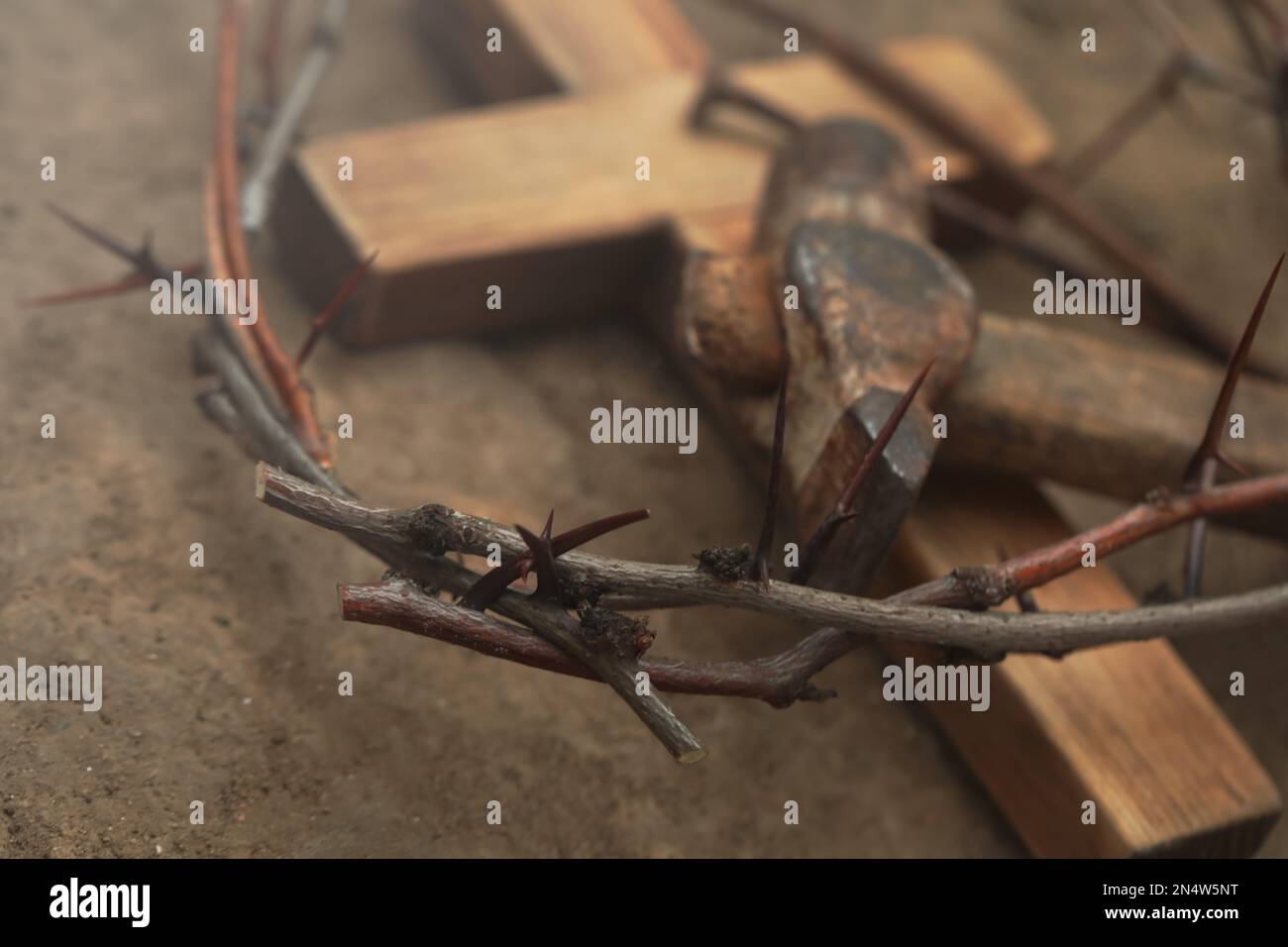 Corona de espinas, cruz de madera y martillo en el suelo, primer plano. Atributos de Pascua Foto de stock