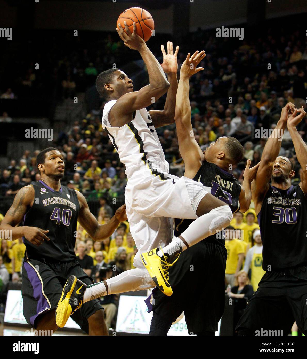 Oregon's Damyean Dotson, center, is fouled driving to the basket past