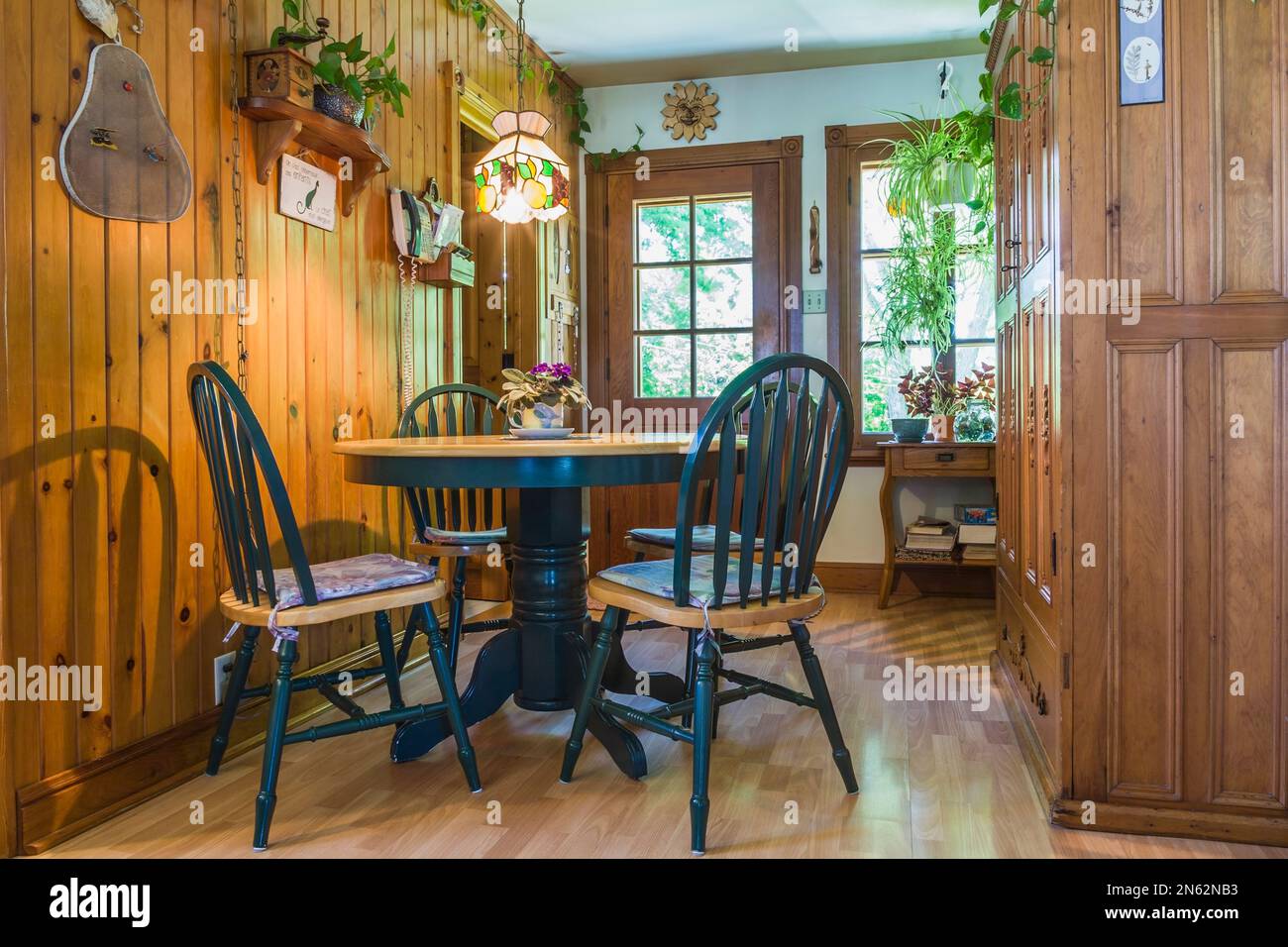 Cocina de campo con mesa de comedor de madera de cerezo y sillas de  respaldo alto, gabinetes de madera de pino, piso laminado de madera dentro  de la antigua casa de estilo