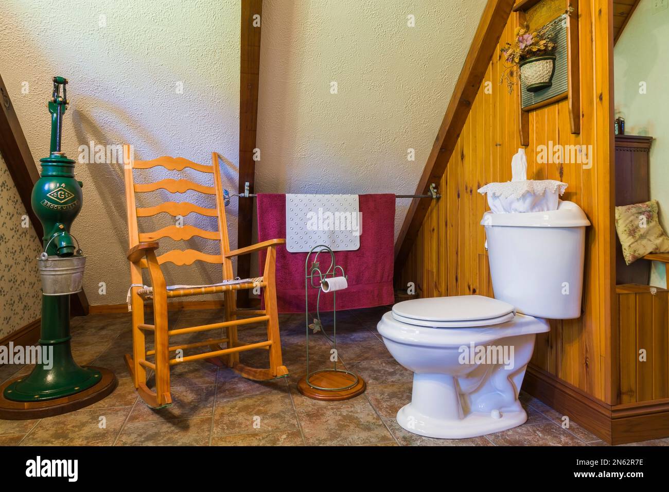 wc de porcelana blanca y mecedora de madera antigua en suite dentro de la antigua casa de 1927. Foto de stock